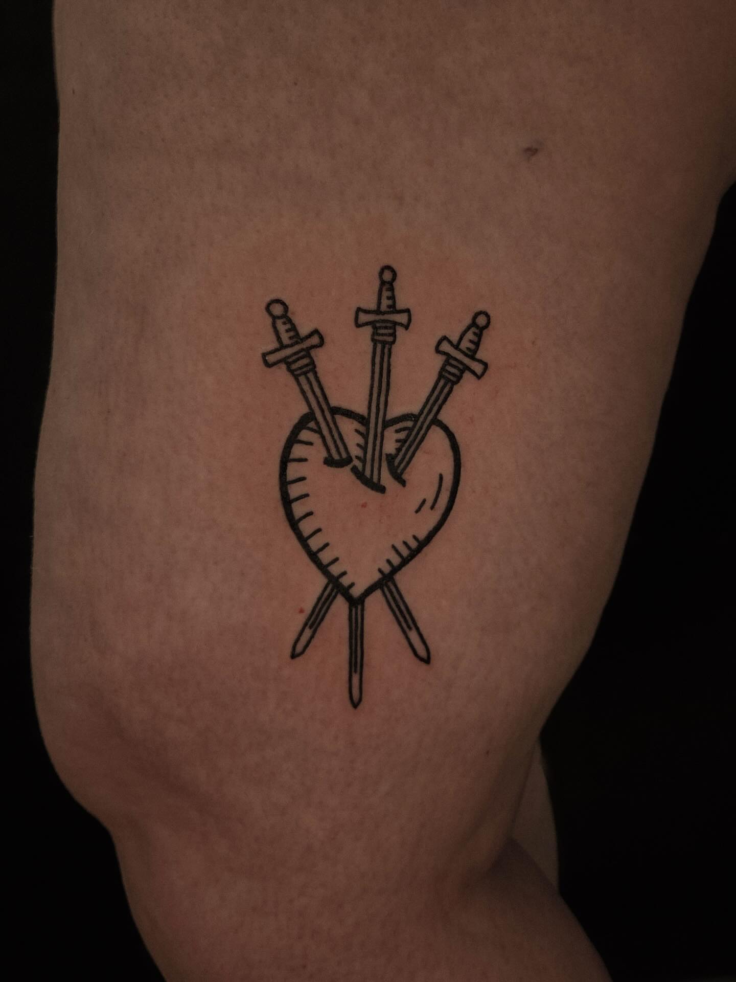 Heart with swords black and grey tattoo on the thigh by ashley blyght