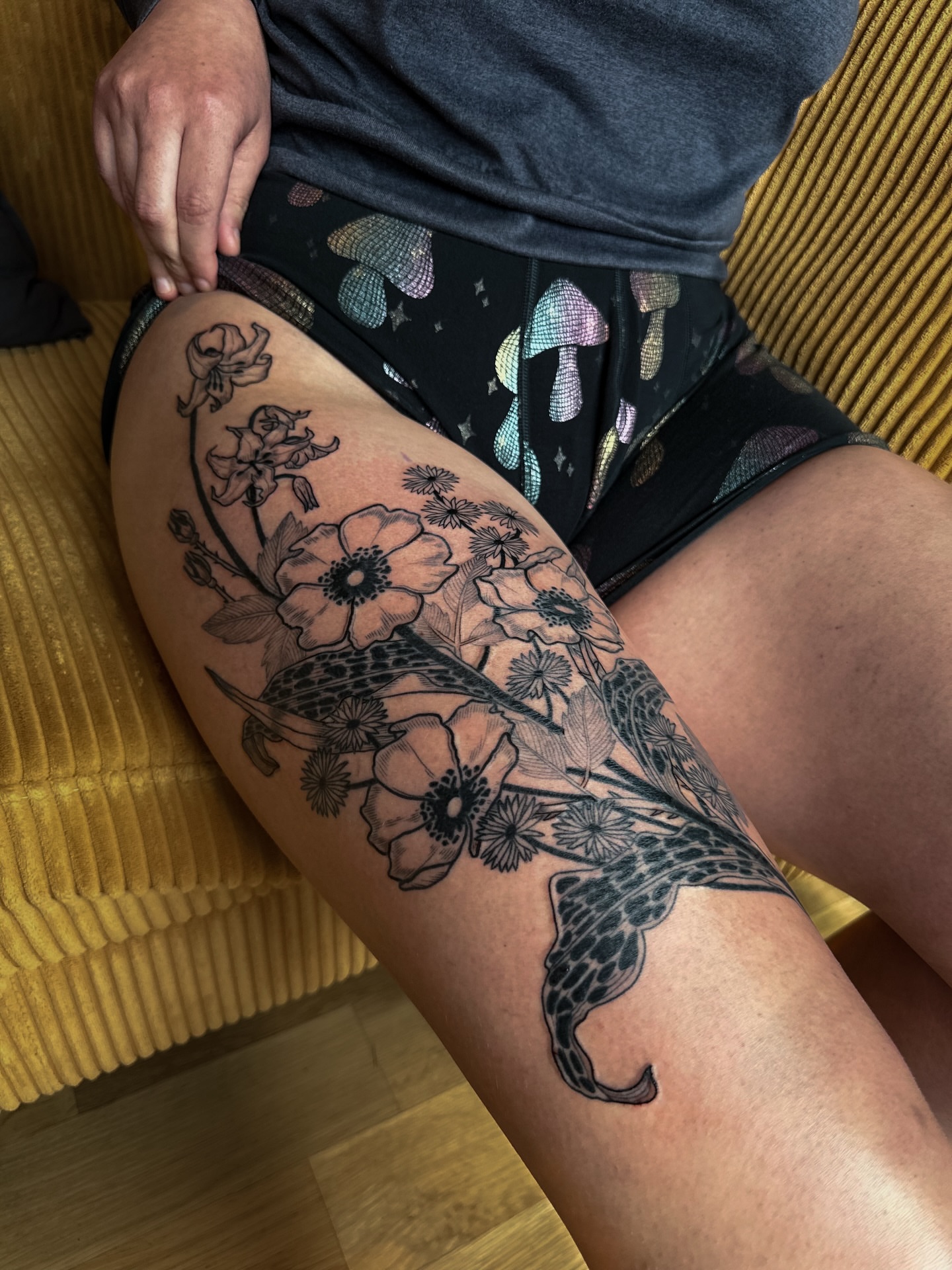 Flowers and bird black and grey tattoo on the thigh by Alexandra Gray