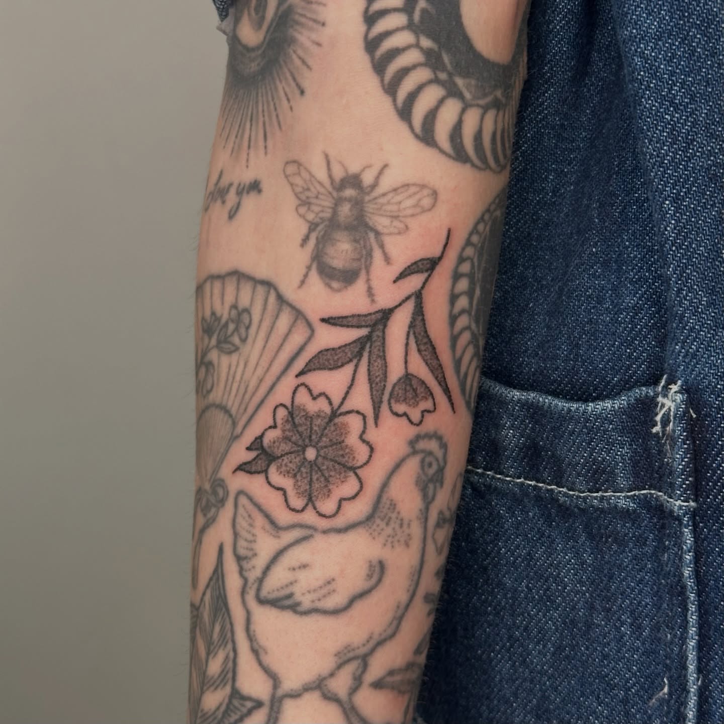 Bee and floral black and grey tattoo on the forearm by paulina