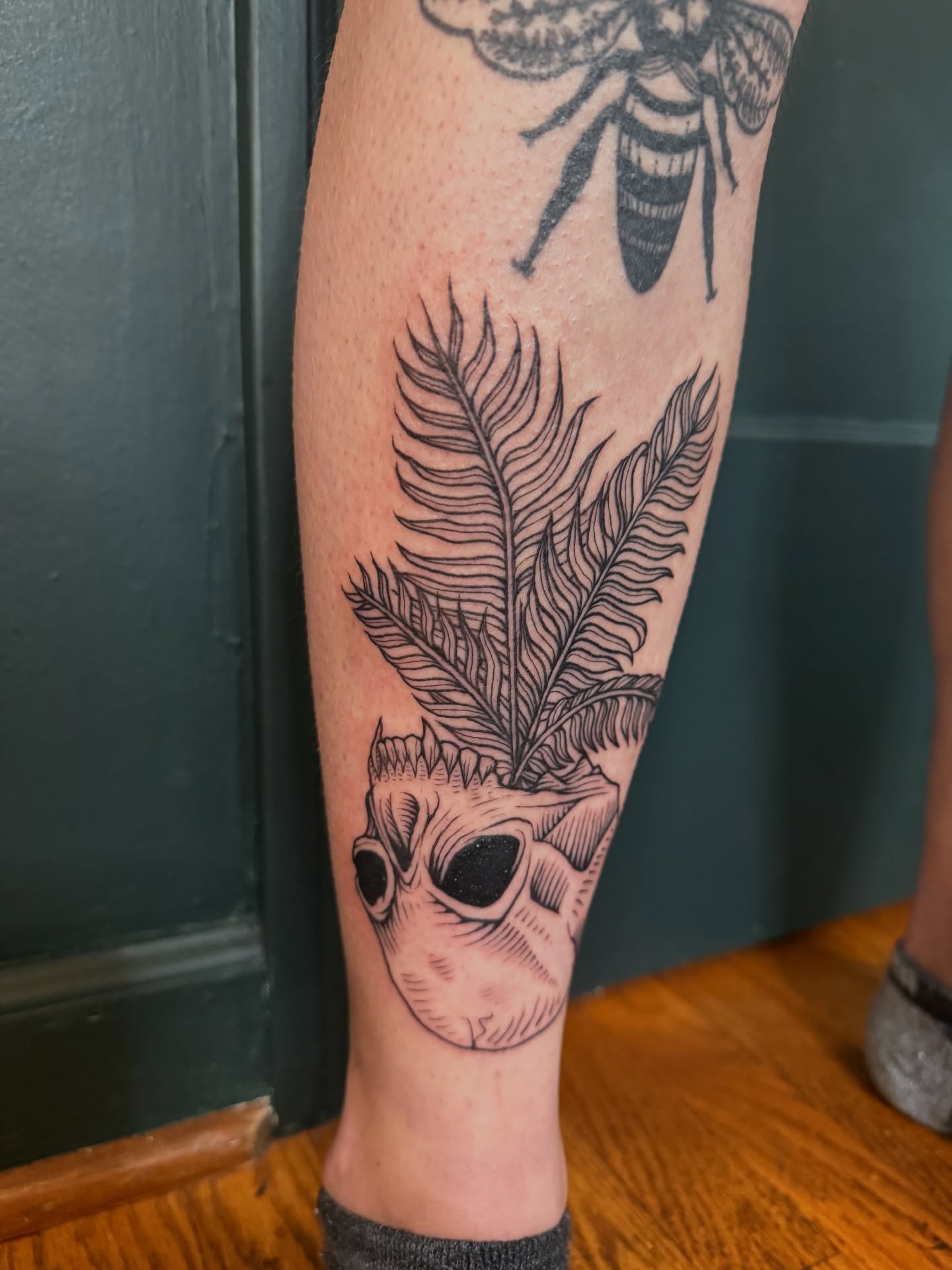 Skull with feathers black and grey tattoo on the forearm by Paul DeVay
