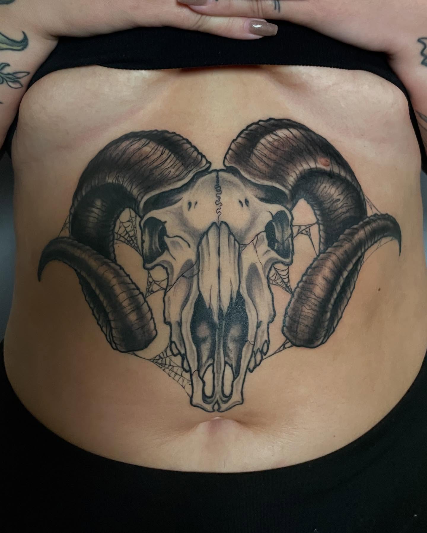 Ram skull black and grey tattoo on the torso by Riley Borne