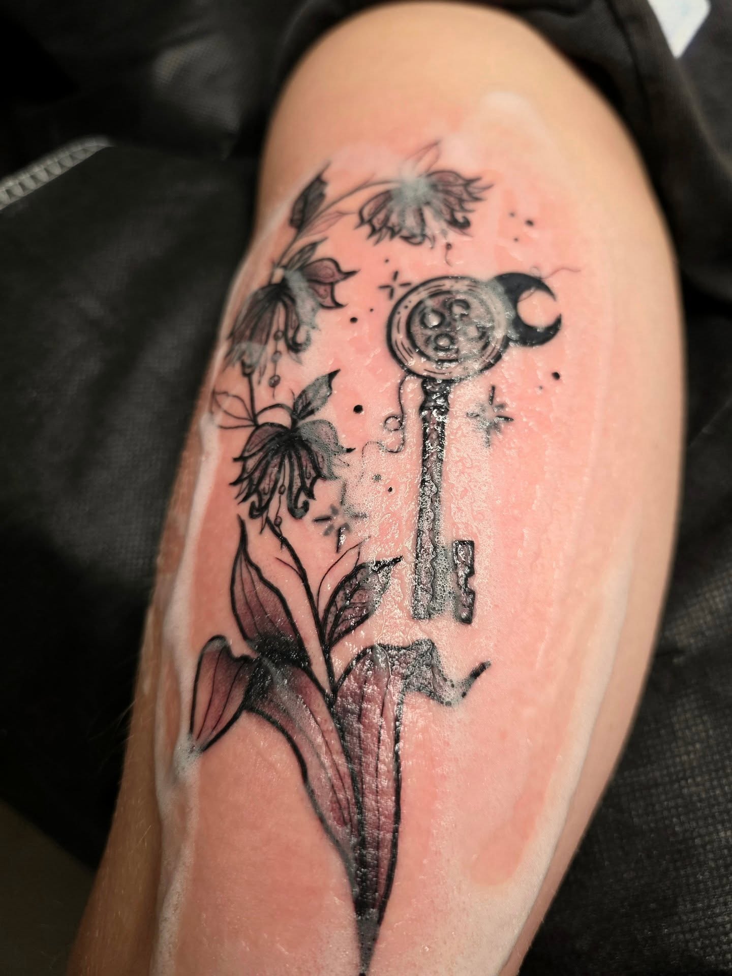 Key and floral black and grey tattoo on the thigh by ☻ Addie