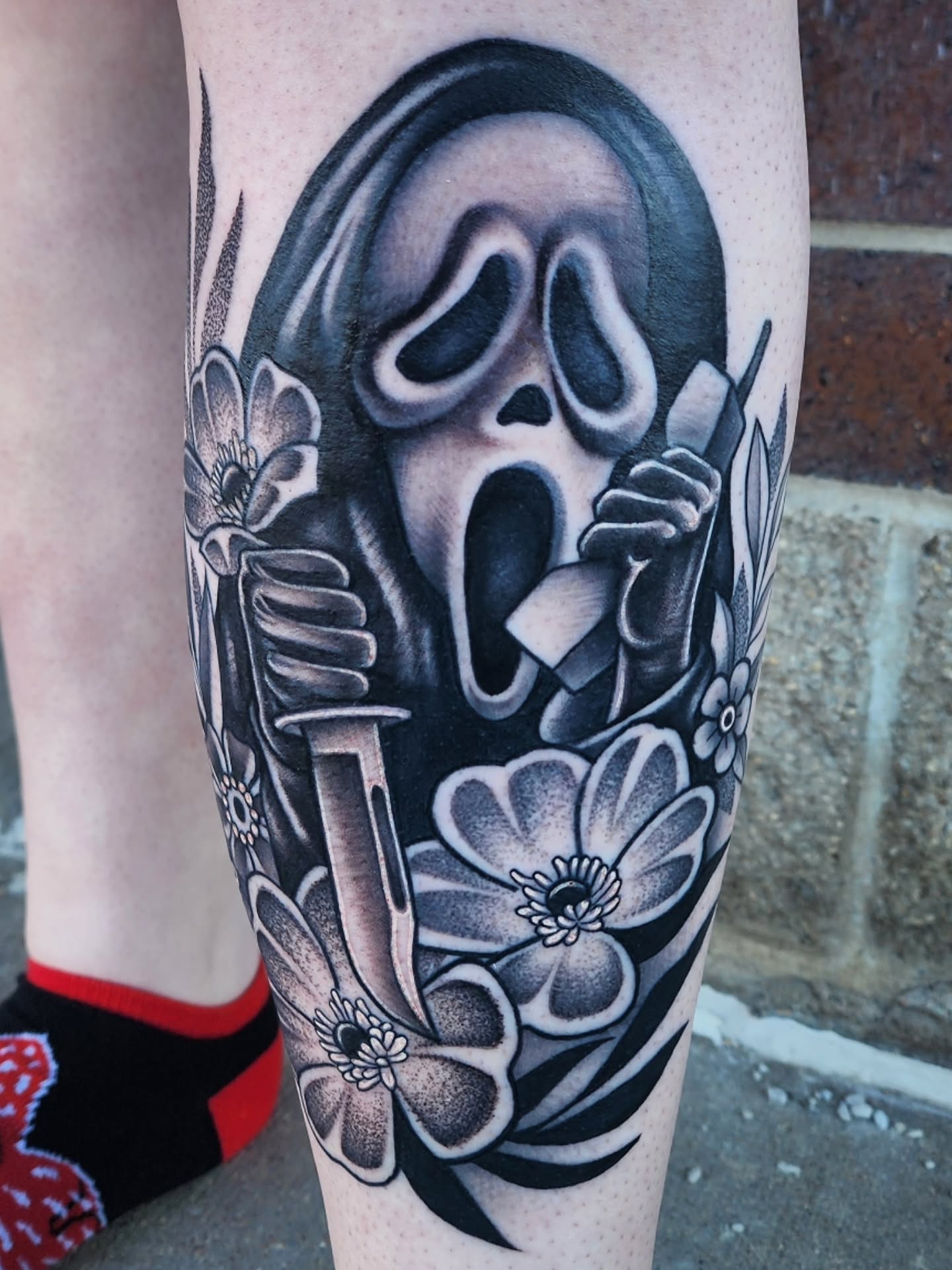 Scream mask black and grey tattoo on the forearm by Shawna Goettsche
