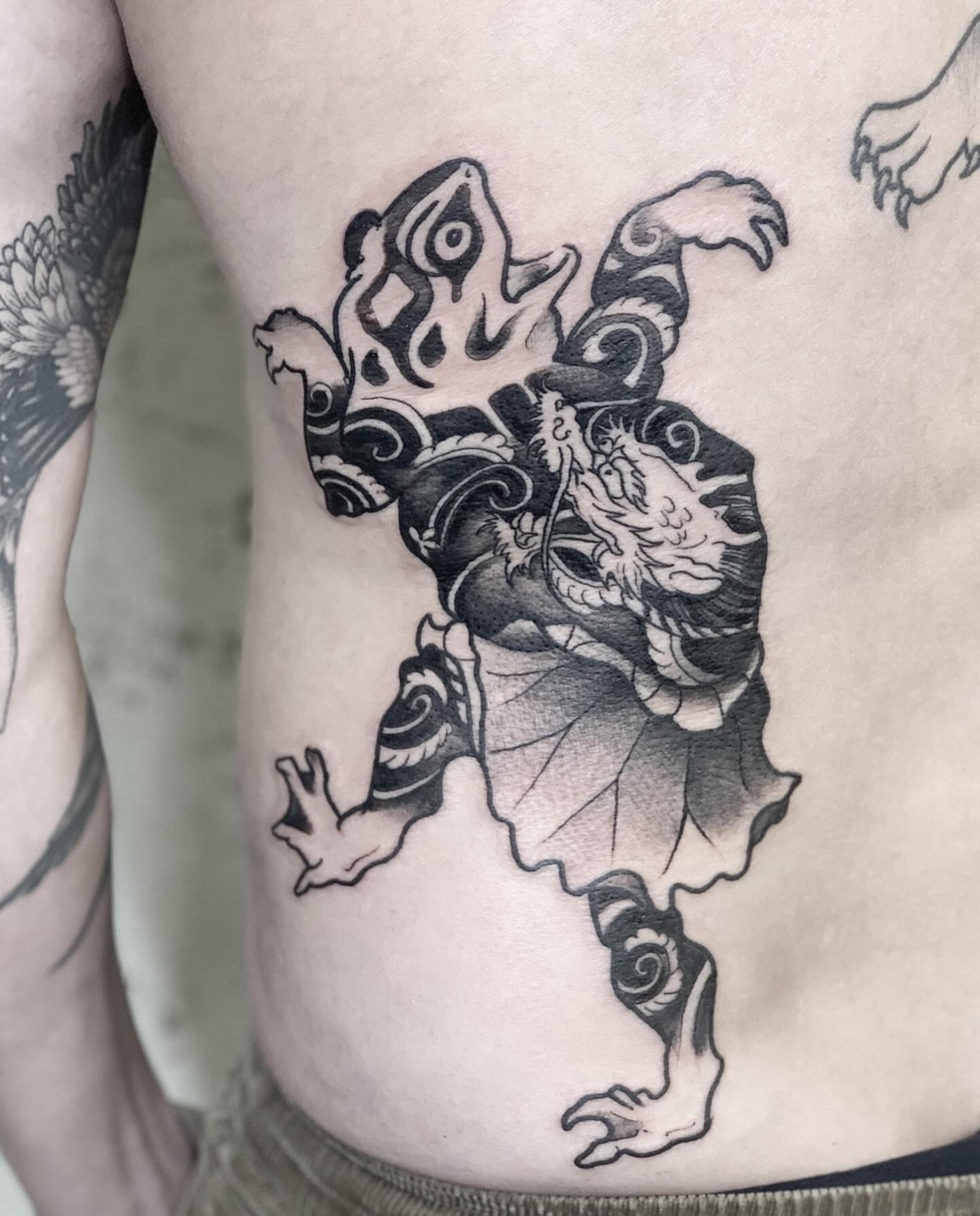 Frog black and grey tattoo on the ribs by Elvira Savchuk