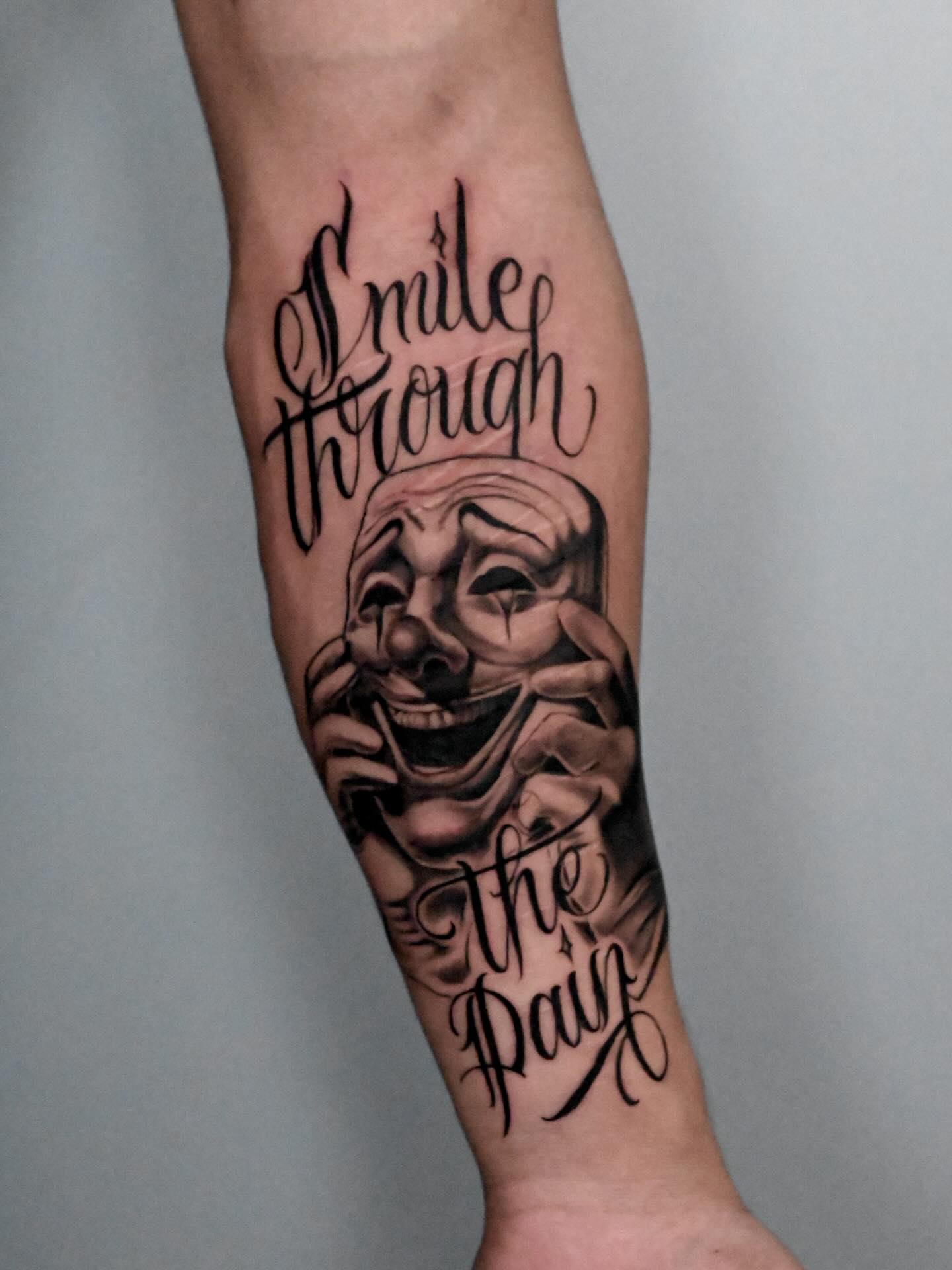 Smile through pain black and grey tattoo on the forearm by Stilow Memphis Tattoo Artist, Memphis, Tennessee