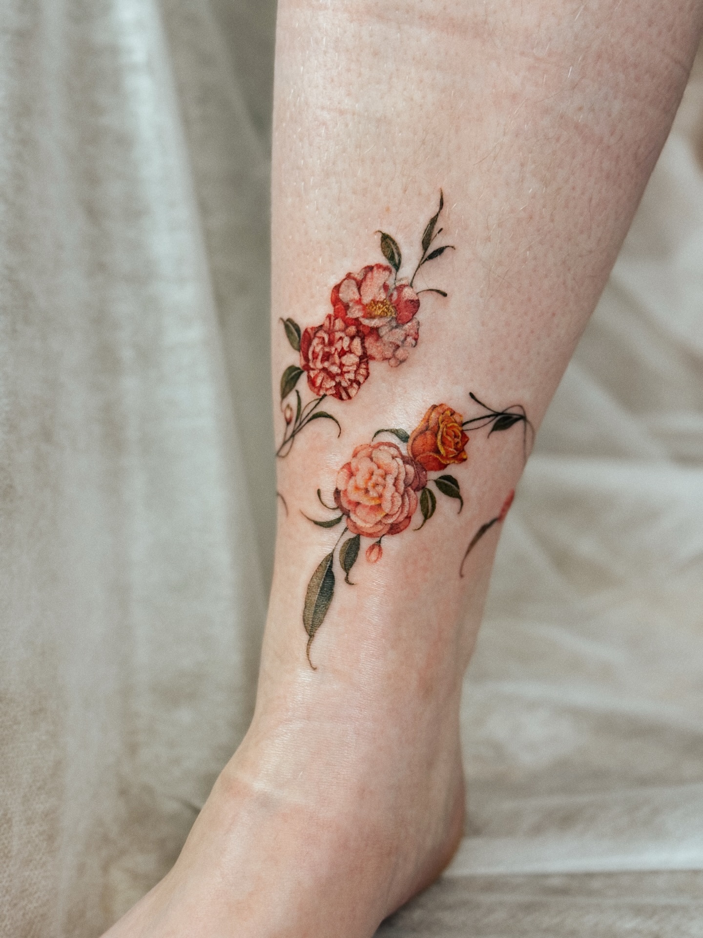 Floral arrangement watercolor tattoo on the calf by Andrea Evangelista