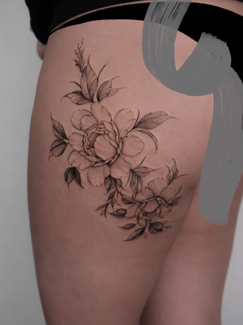 Floral bouquet black and grey tattoo on the thigh by Anastasiia