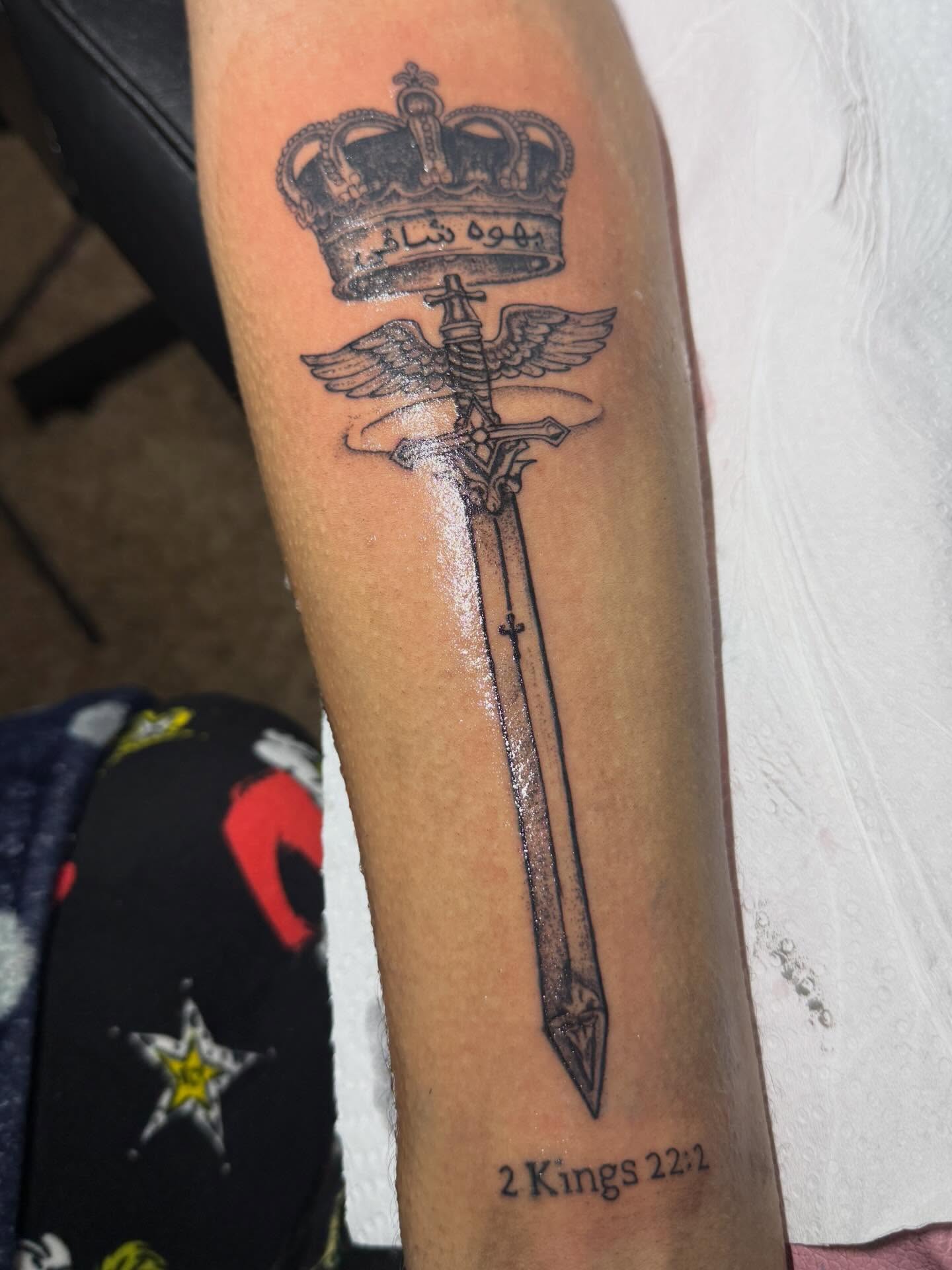 Sword with wings and crown black and grey tattoo on the forearm by Destini