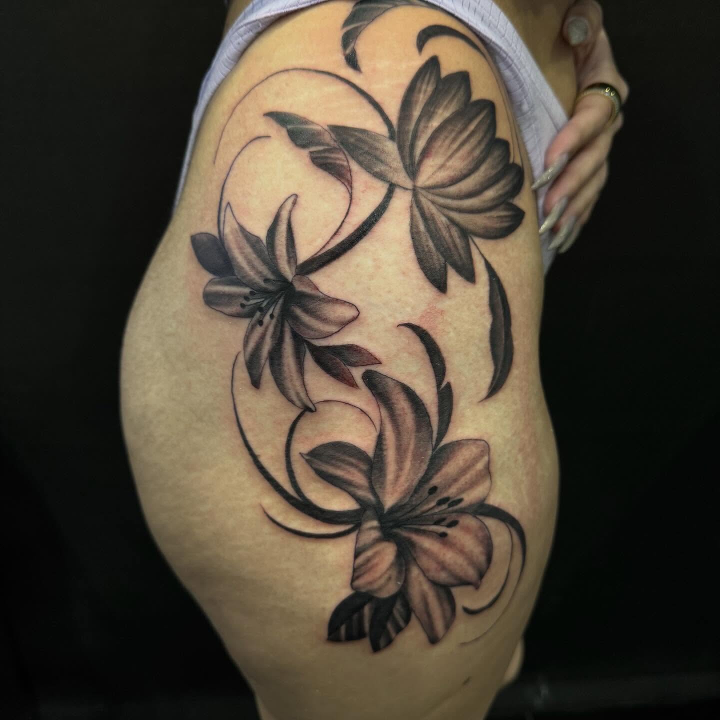 Lilies black and grey tattoo on the thigh by Brian Herrera
