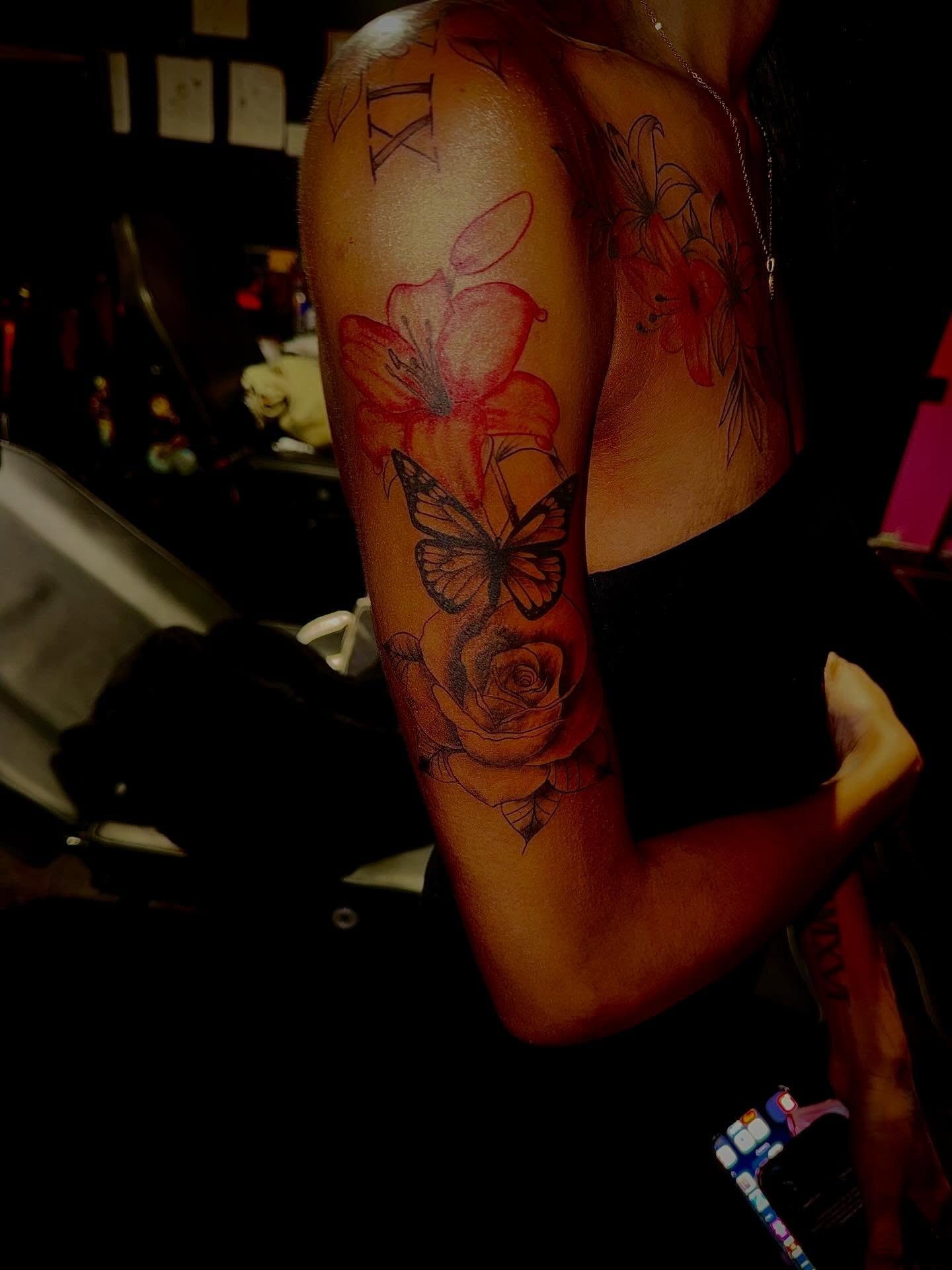 Flowers and butterfly realism tattoo on the upper arm by Clifford Jordan