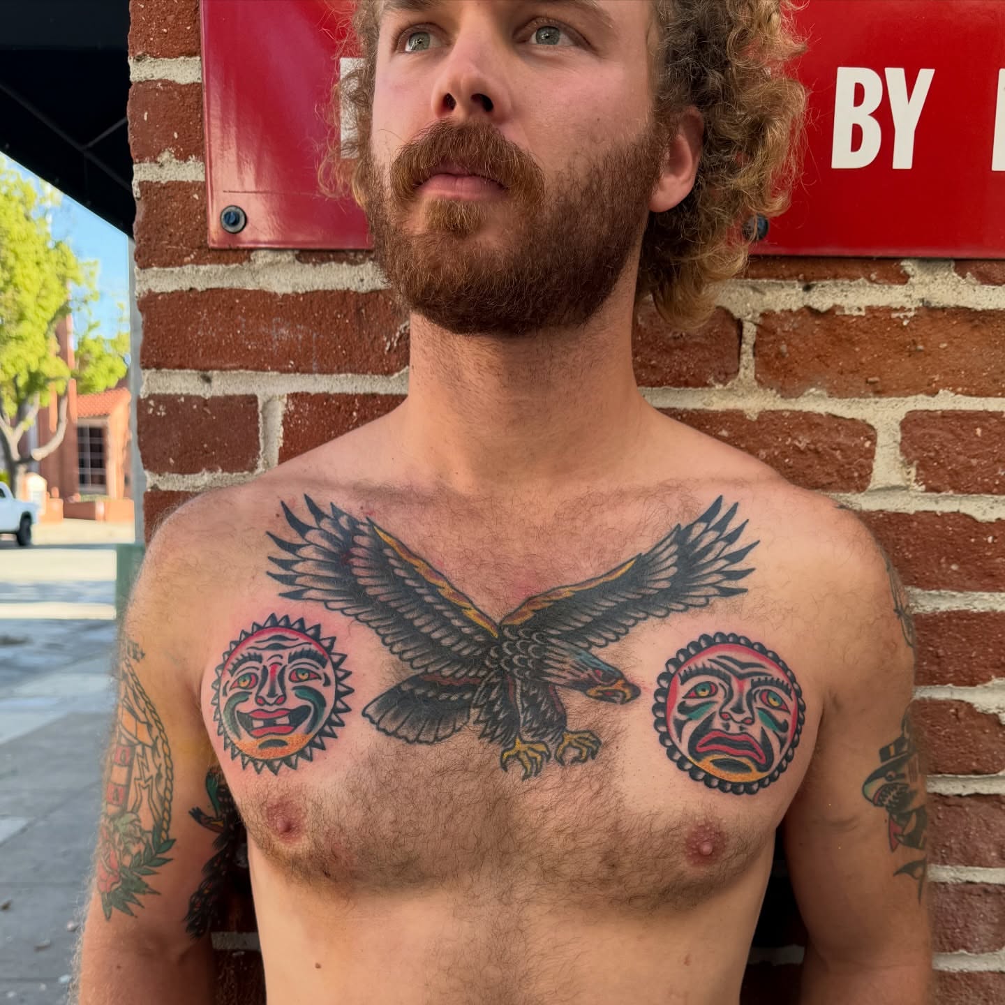 Eagle and sun masks American traditional tattoo on the chest by Erik Sheppard