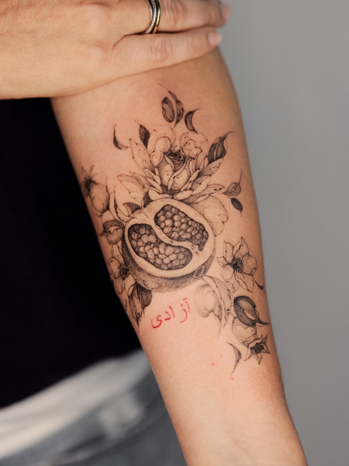 Pomegranate and floral arrangement realism tattoo on the forearm by Maria