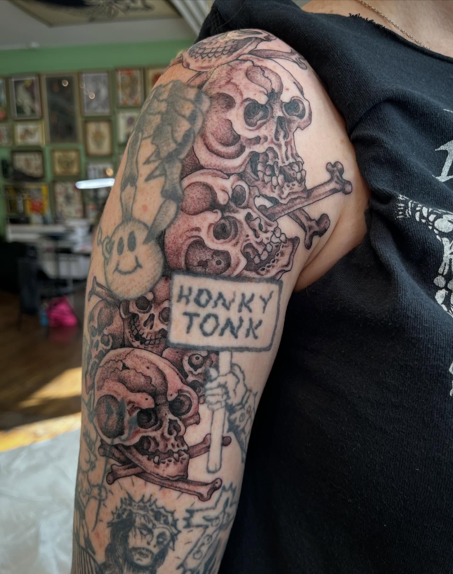 Skulls and bones realism tattoo on the upper arm by Chris Kline