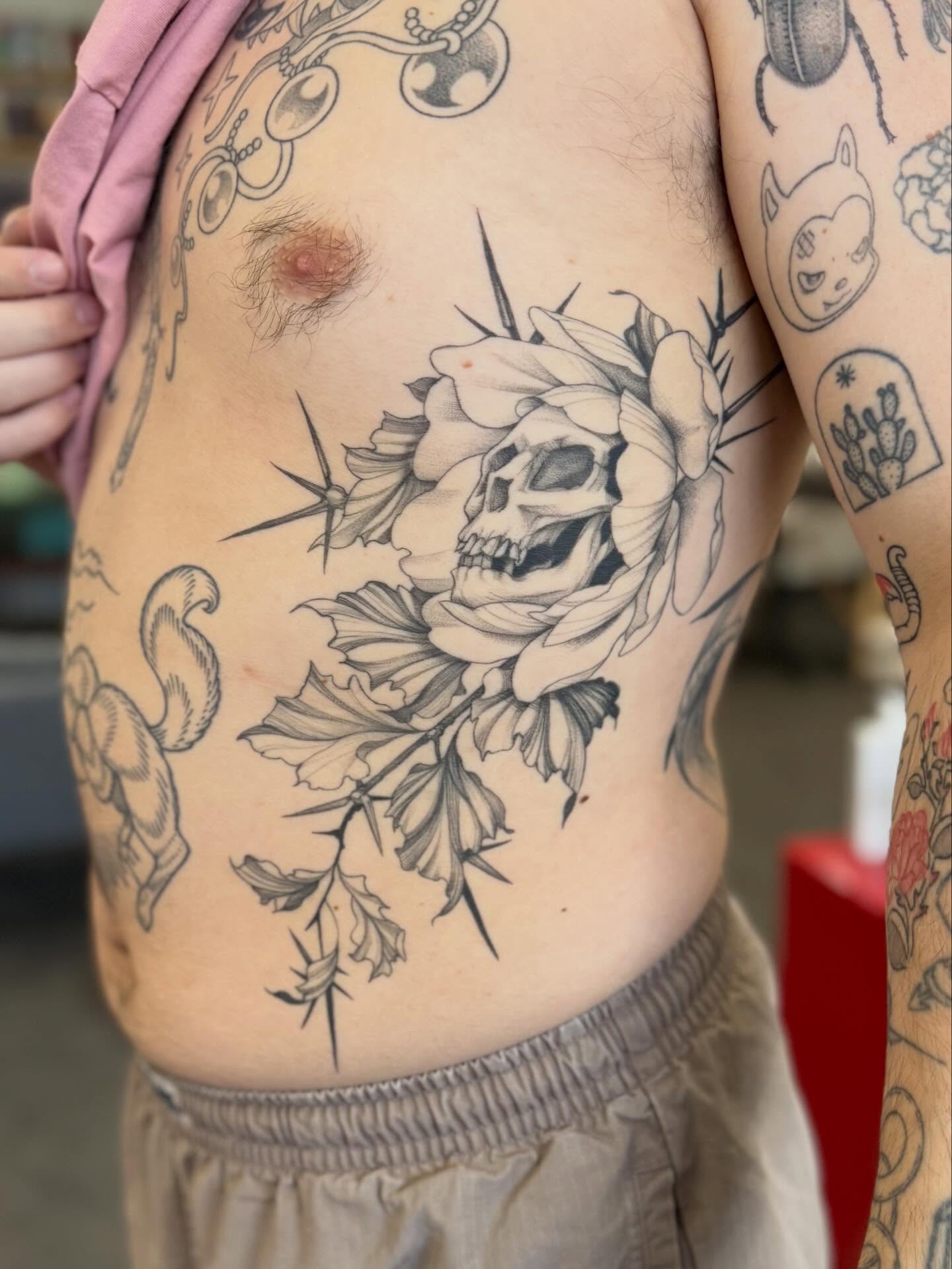 Skull and flower realism tattoo on the ribs by Peter Harren