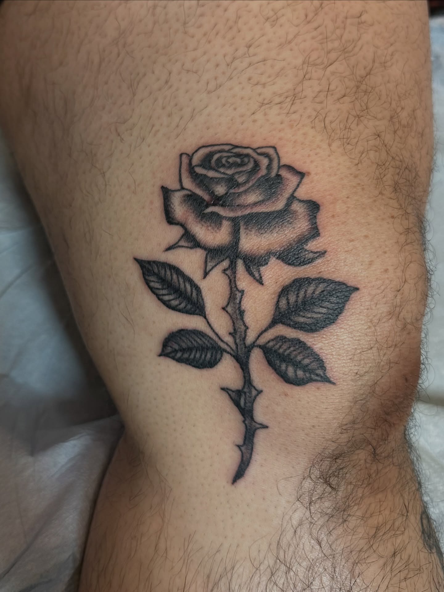 Rose black and grey tattoo on the thigh by Hayley Hendrick