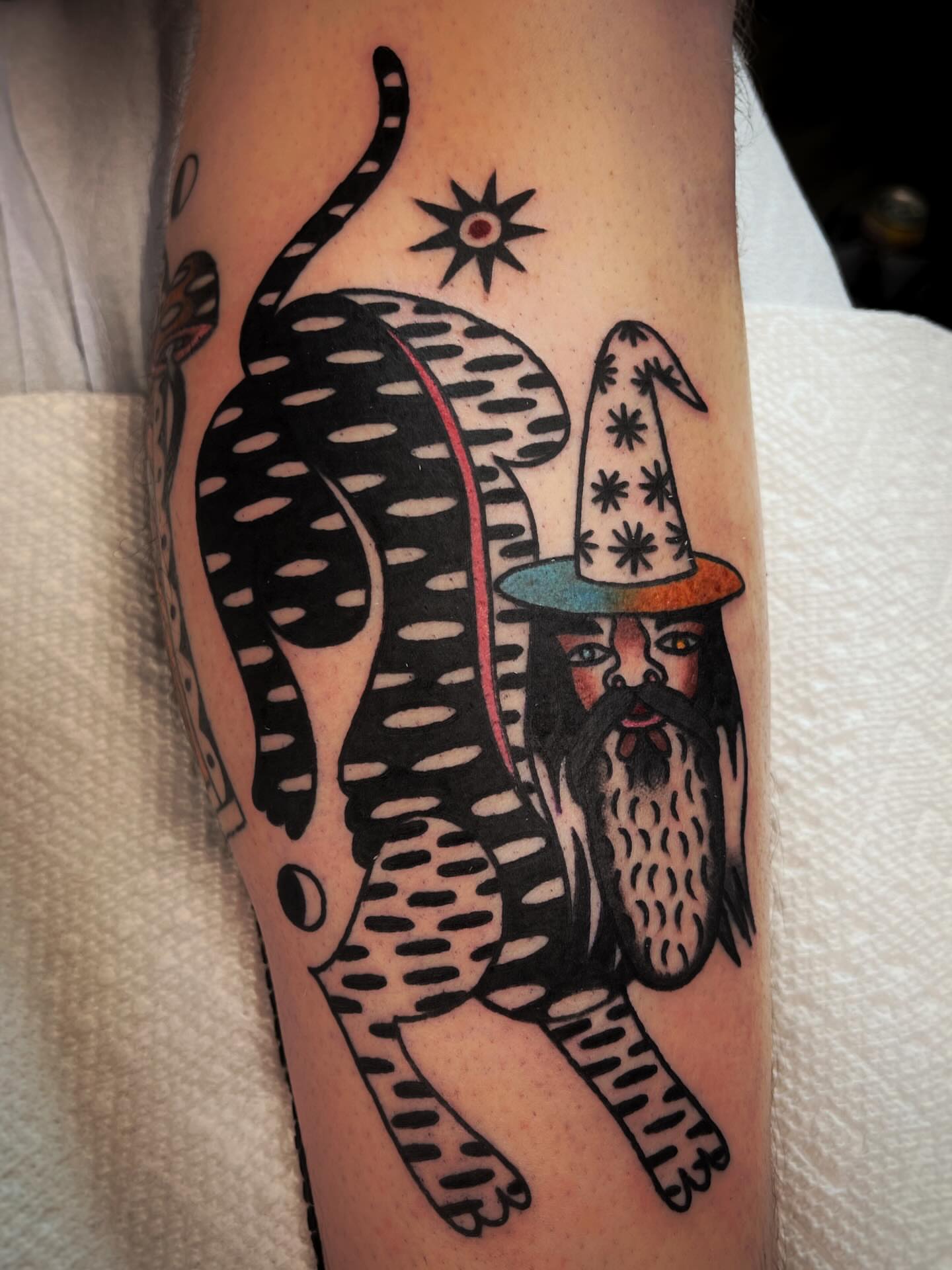 Cat and wizard American traditional tattoo on the forearm by Manee Friday