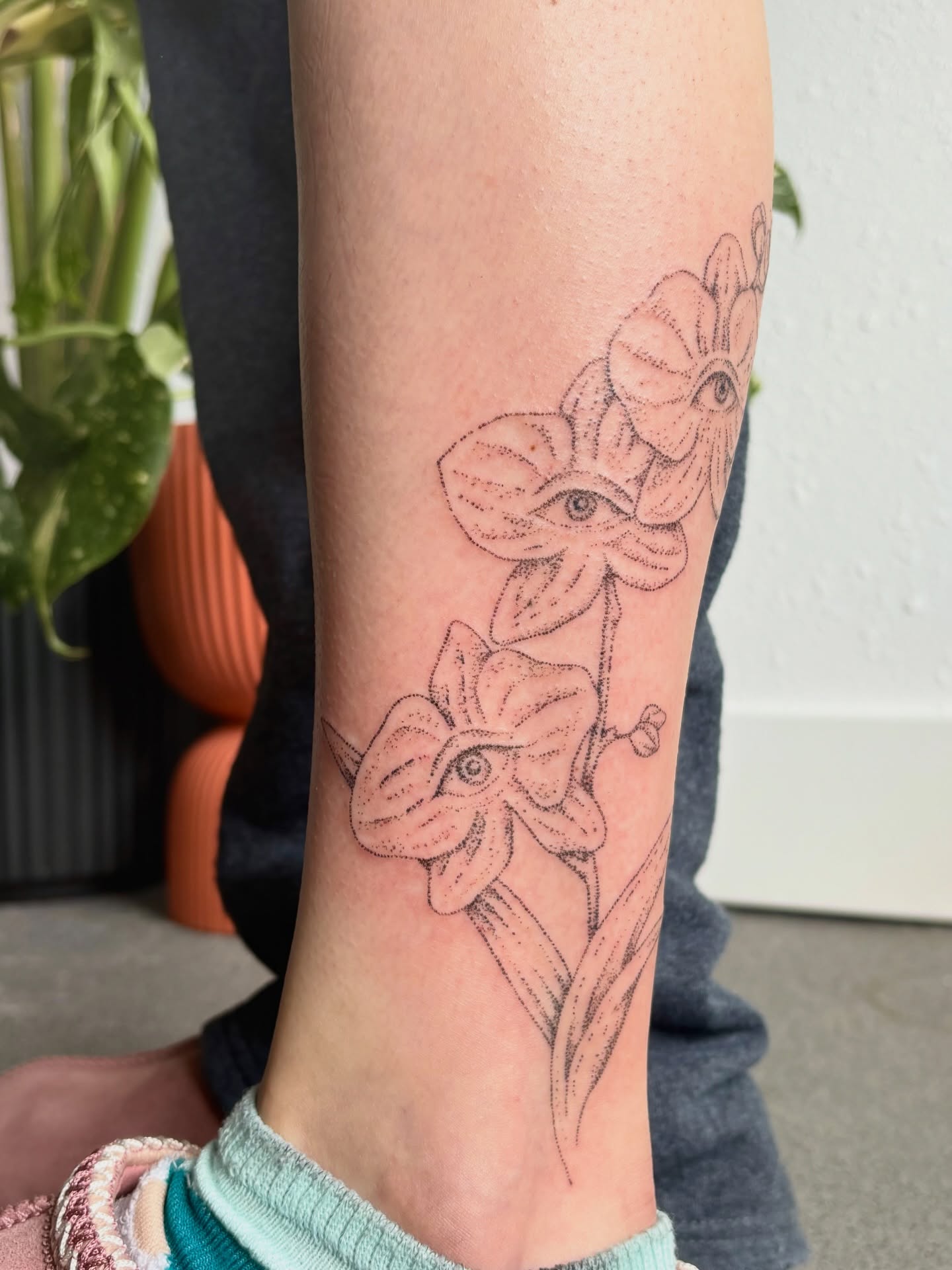 Flowers with eyes black and grey tattoo on the calf by Ashley, Elk Horn, Iowa