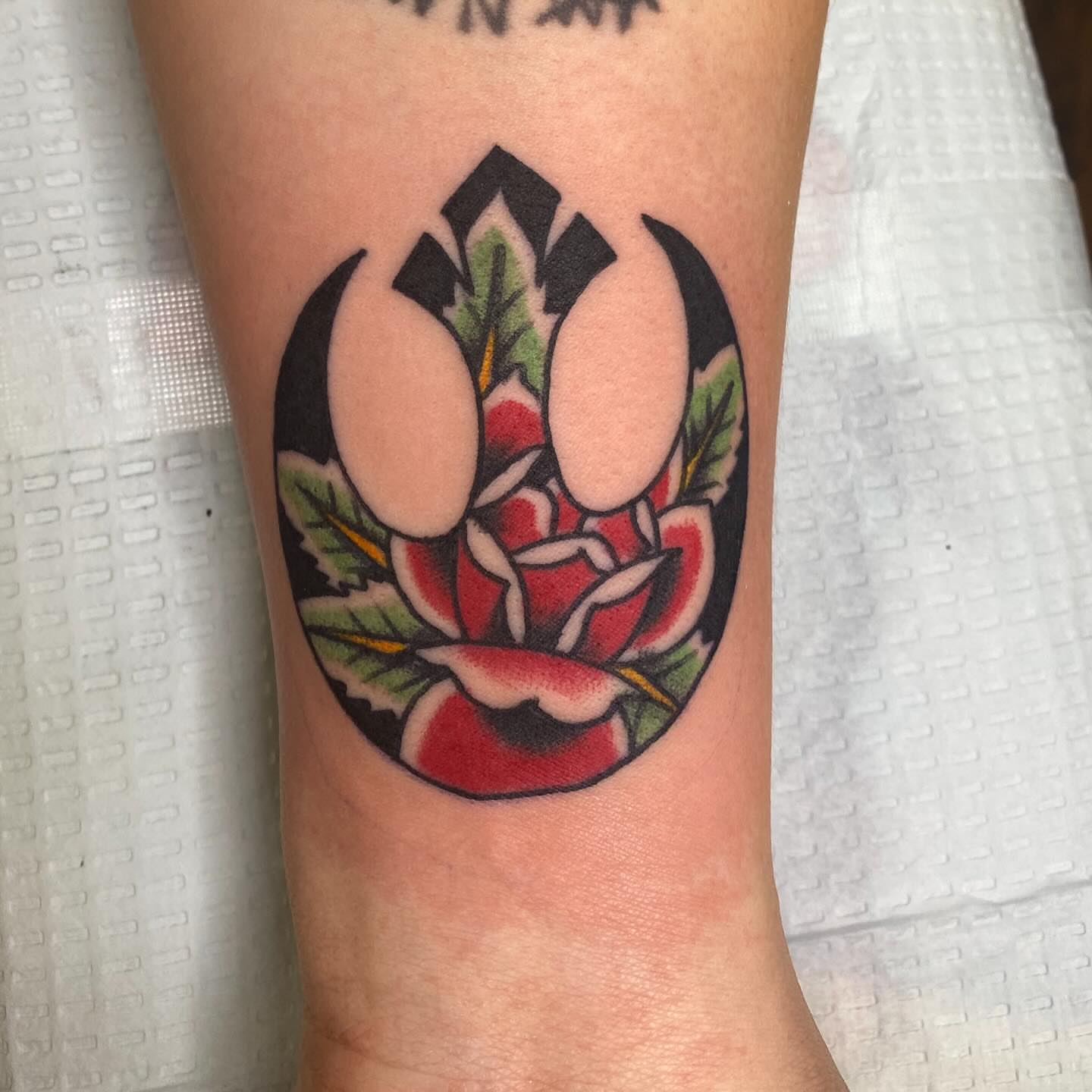 Flower with emblem American traditional tattoo on the forearm by Thomas Cook