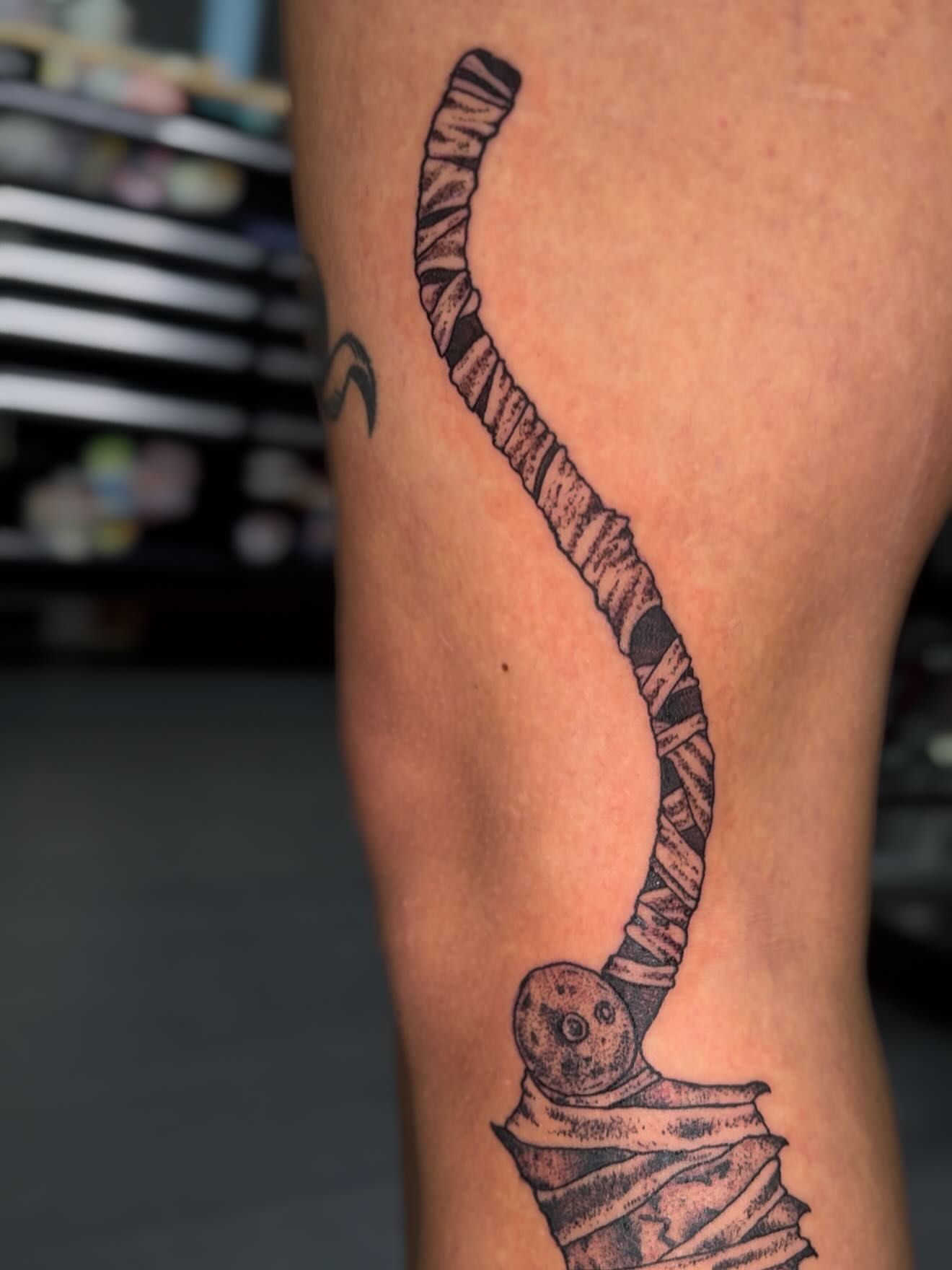 Hockey stick black and grey tattoo on the leg by Erin Morbid