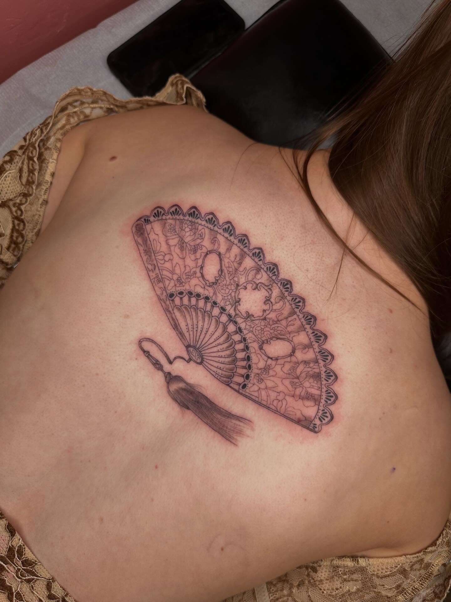 Fan black and grey tattoo on the back by Alex Gunshefski