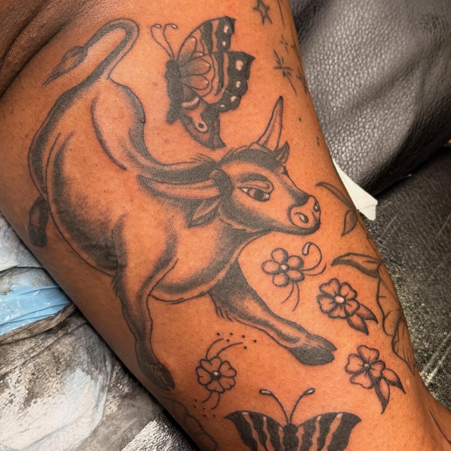 Bull and butterfly black and grey tattoo on the thigh by Megan Sue Causemaker