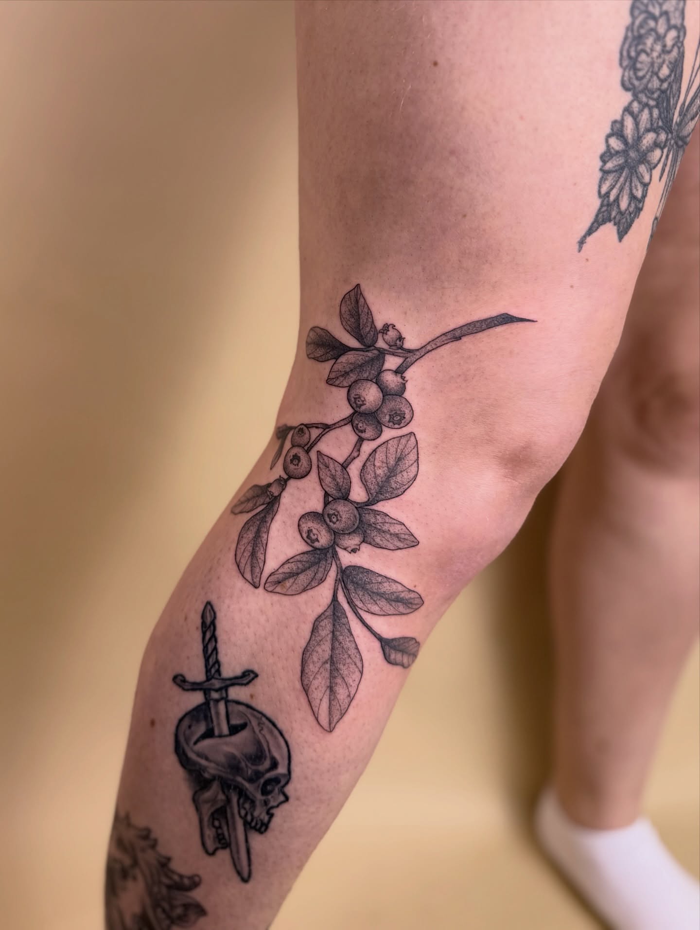 Branch with berries and skull black and grey tattoo on the forearm by Jena Perry