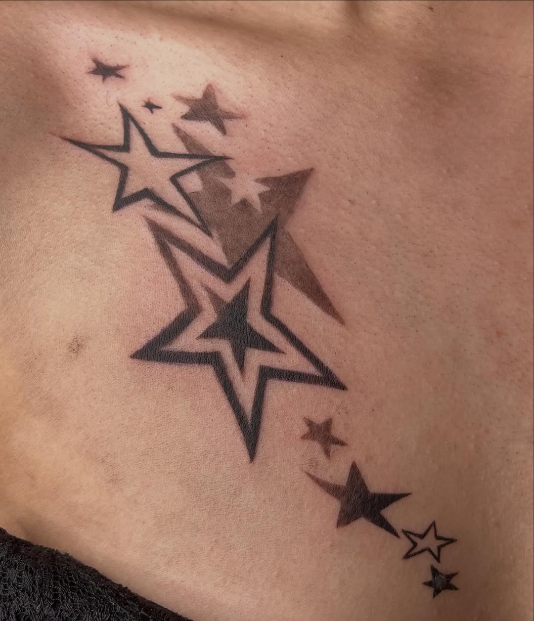 Falling stars fine line tattoo on the chest by Brooke Elayne