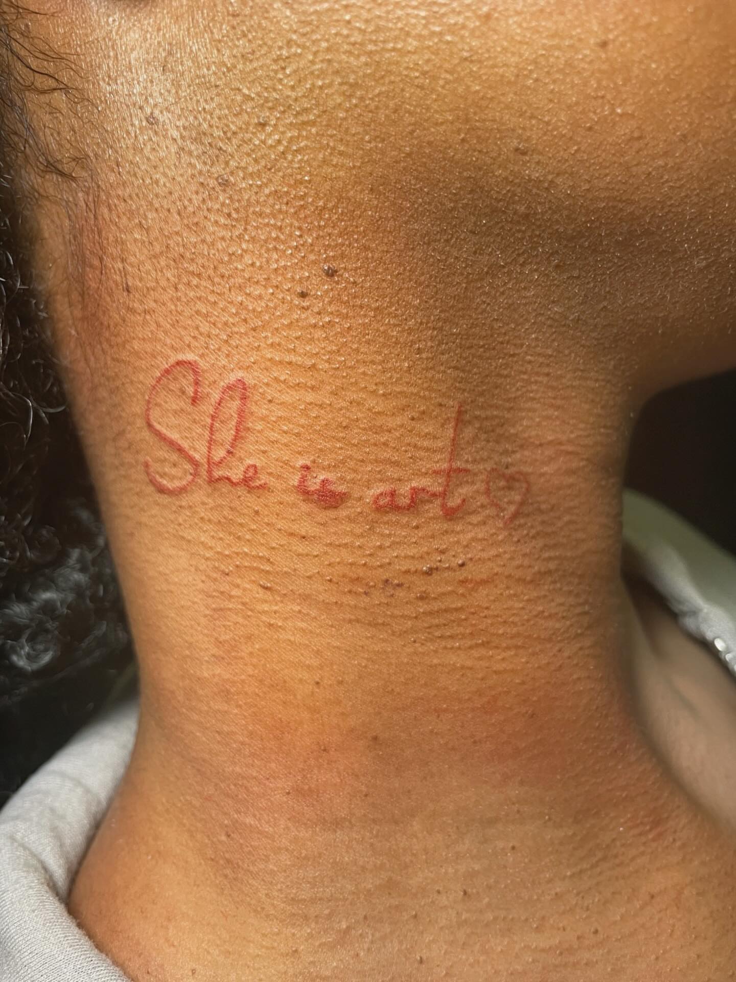 She is art lettering script tattoo on the neck by 𝚃𝙰𝚃𝚃𝙾𝙾 𝙰𝚁𝚃𝙸𝚂𝚃, Charlotte, North Carolina