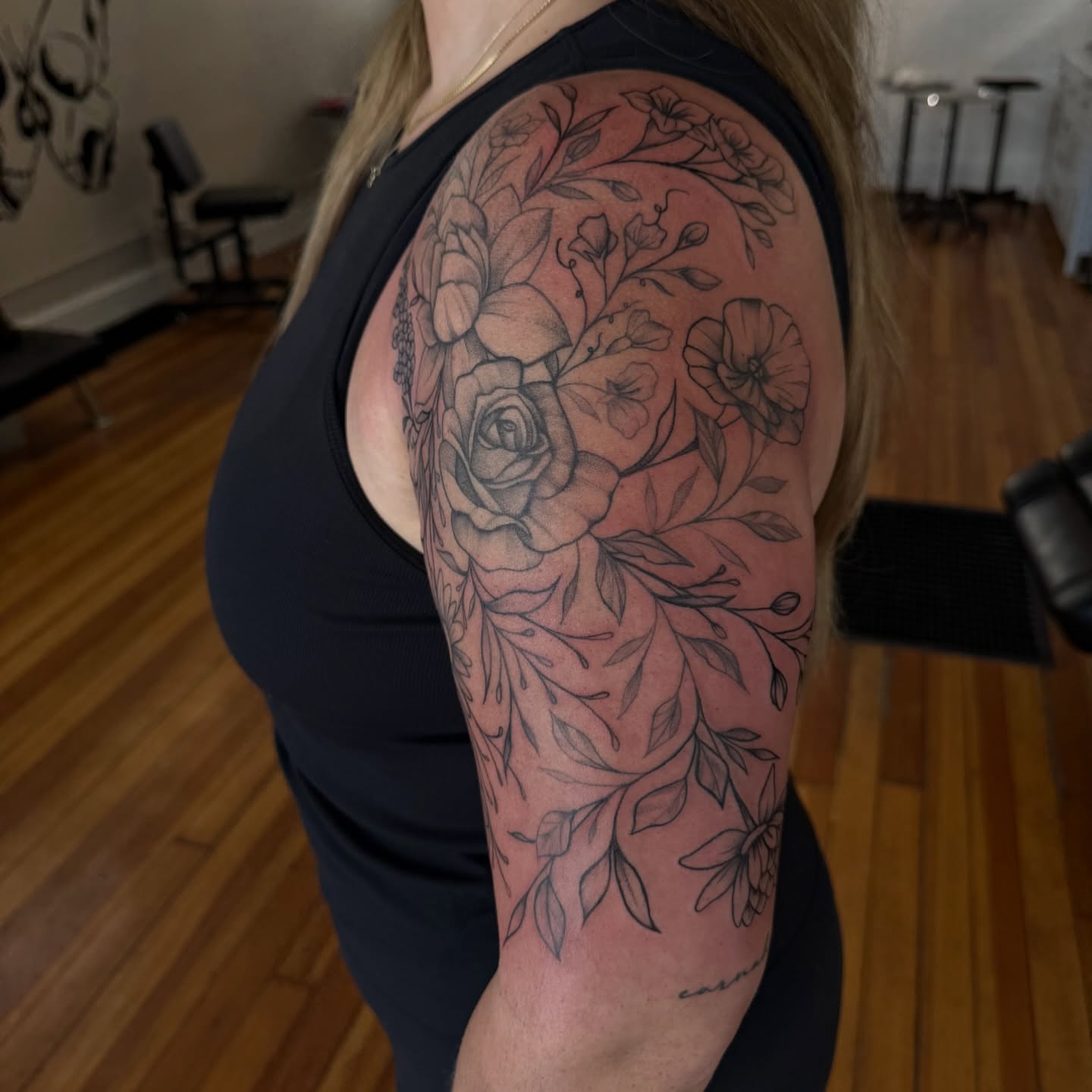 Floral bouquet black and grey tattoo on the upper arm by Lindsay Shriver