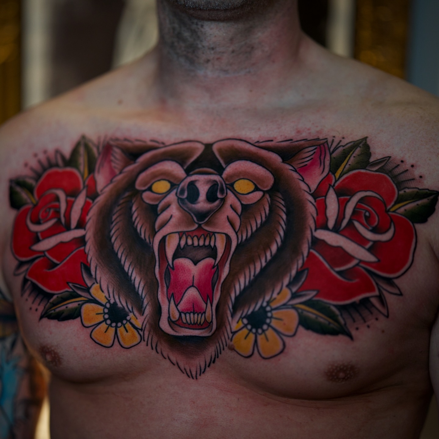 Roaring bear with roses American traditional tattoo on the chest by Justin Hay