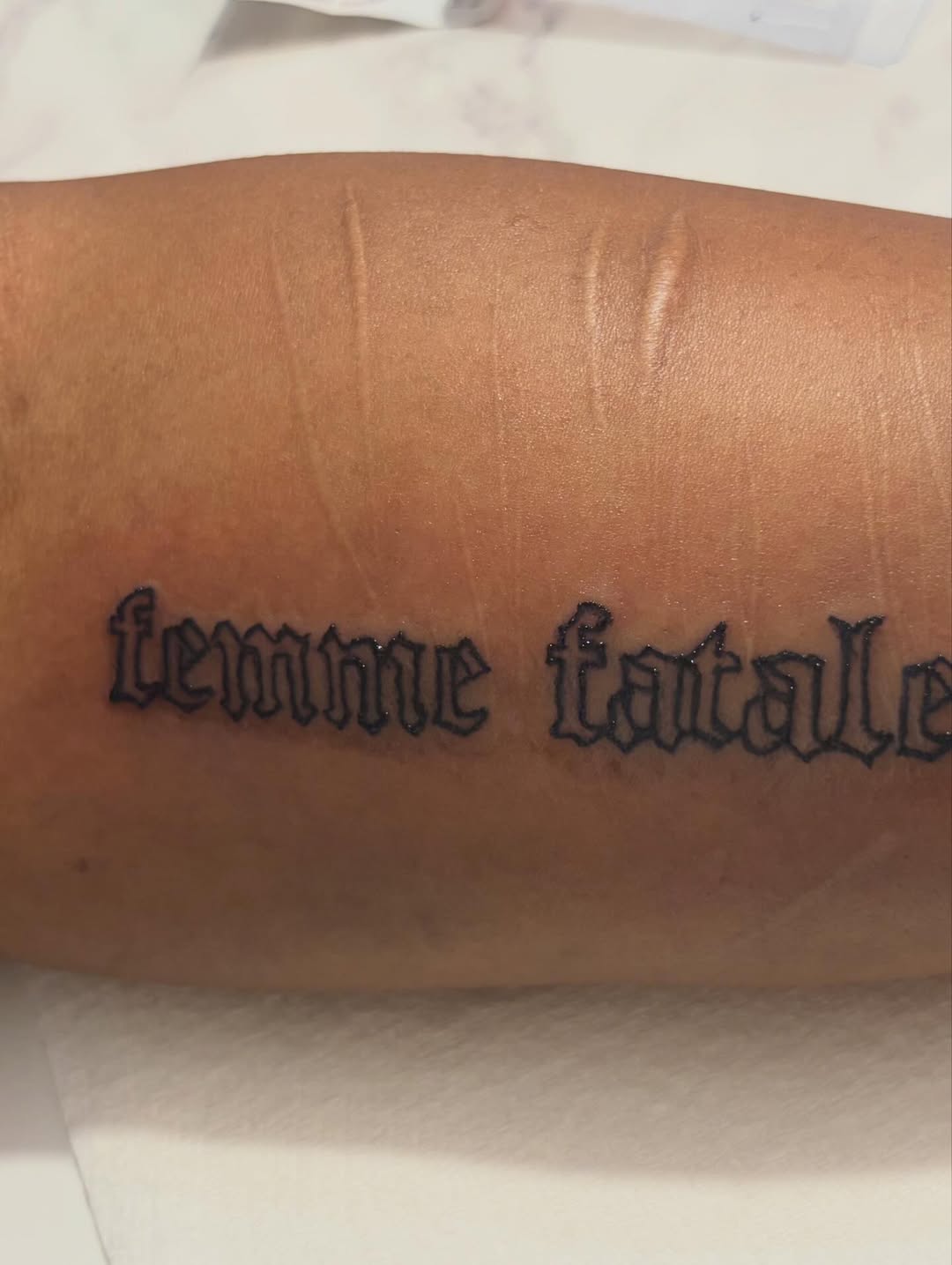 Femme fatale lettering tattoo on the forearm by Jae the artist🫡