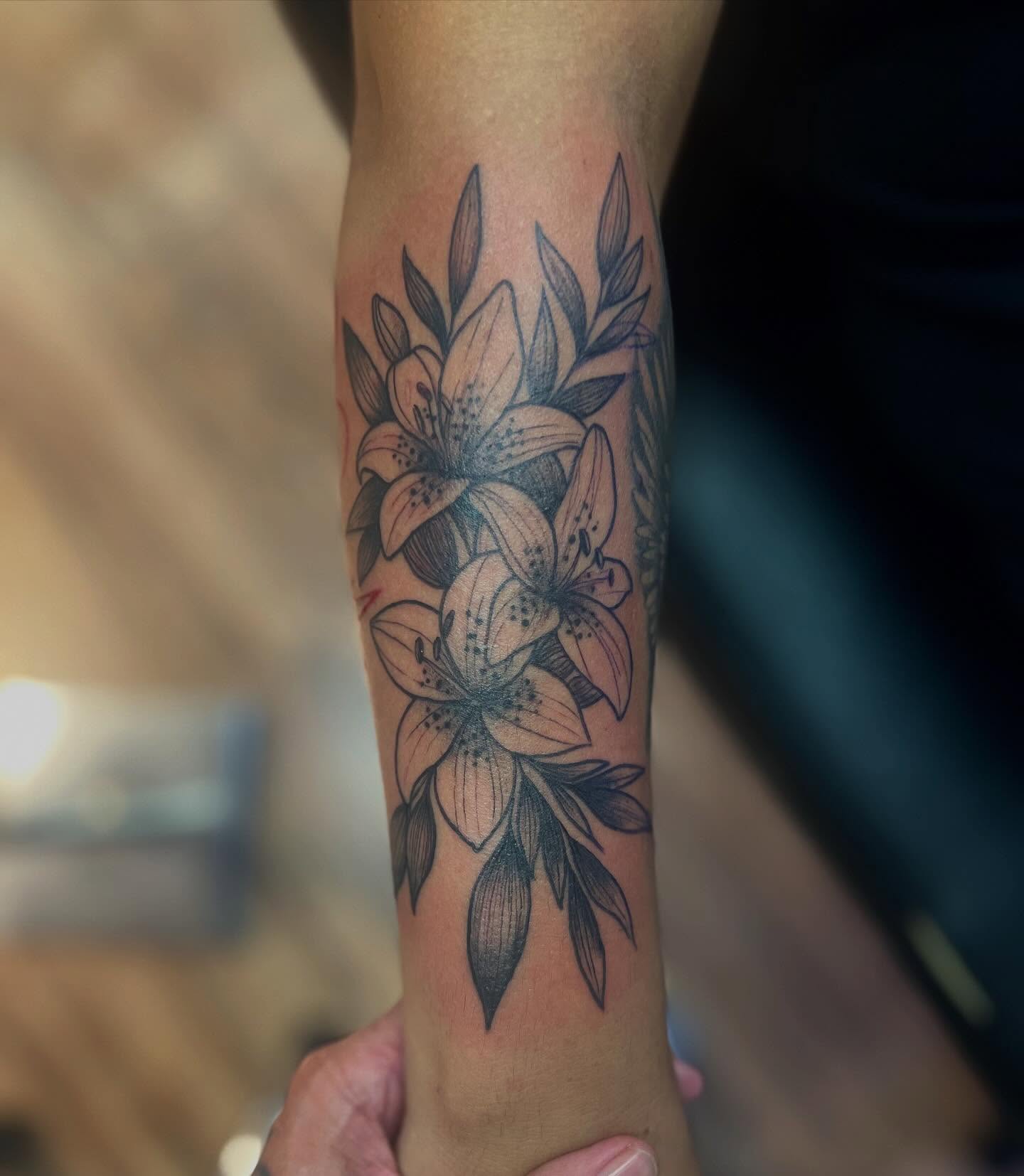Lilies black and grey tattoo on the forearm by Victorian Coleman