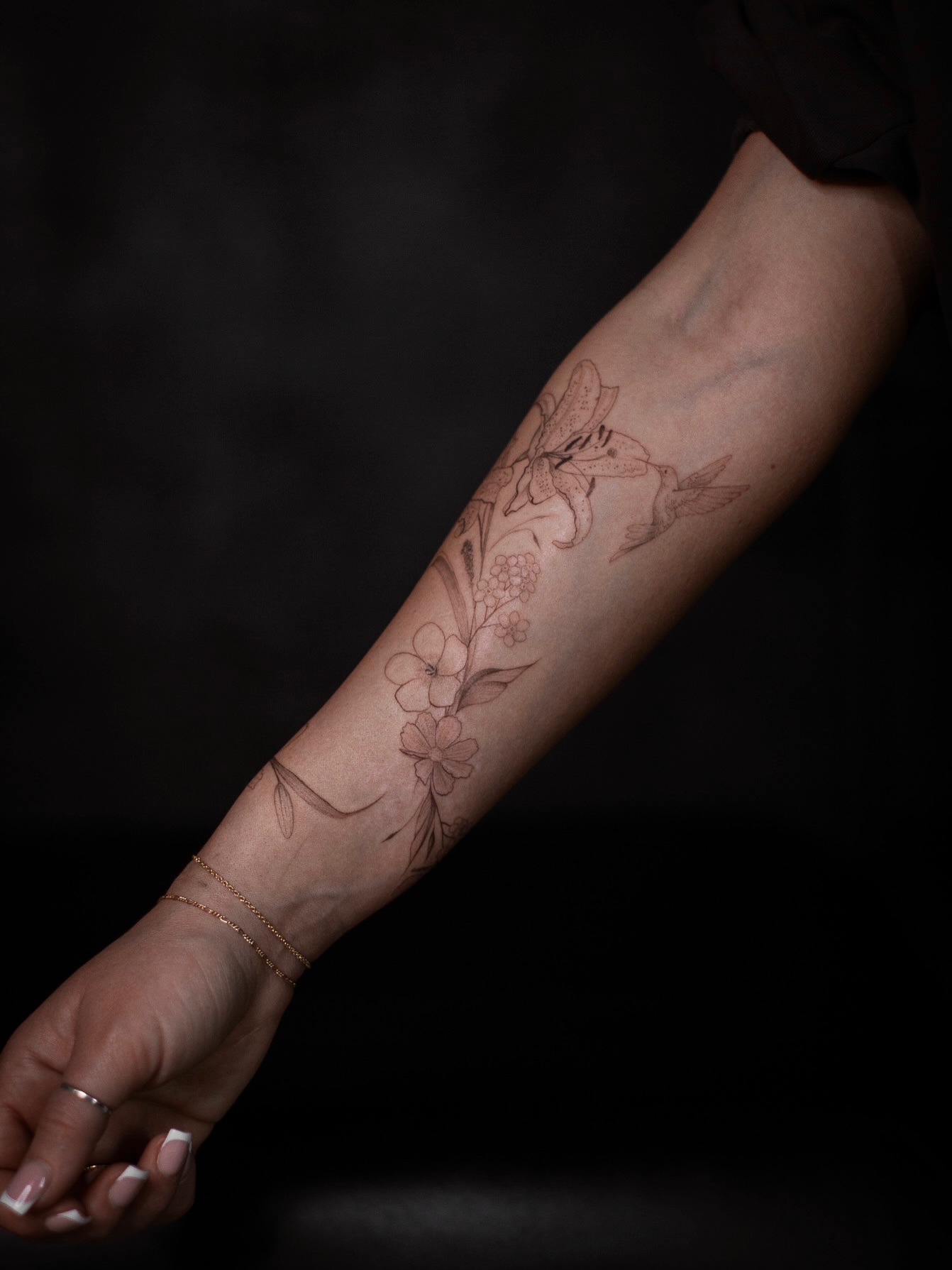 Floral arrangement black and grey tattoo on the forearm by Aries Rising