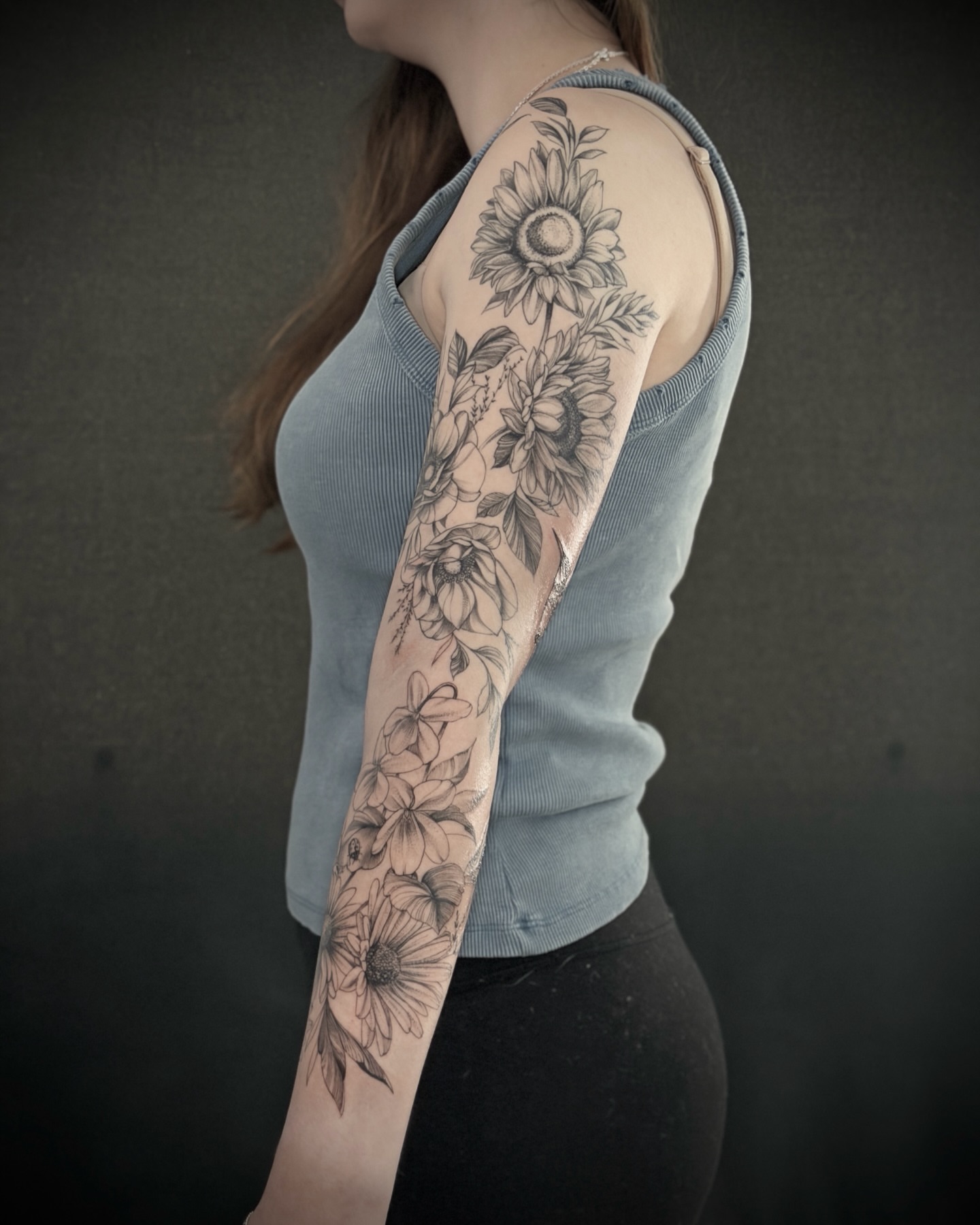 Sunflowers and floral bouquet black and grey tattoo on the upper arm by R e N O T