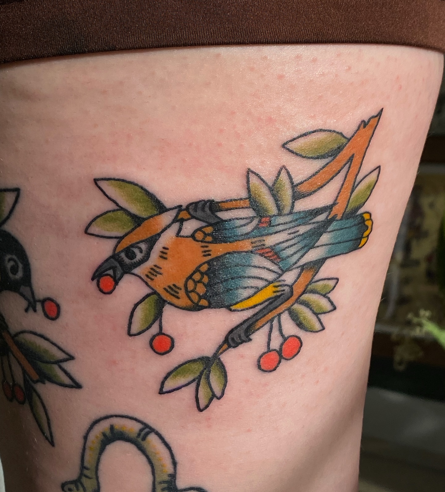 Bird and cherry branch American traditional tattoo on the thigh by Corinne Carter