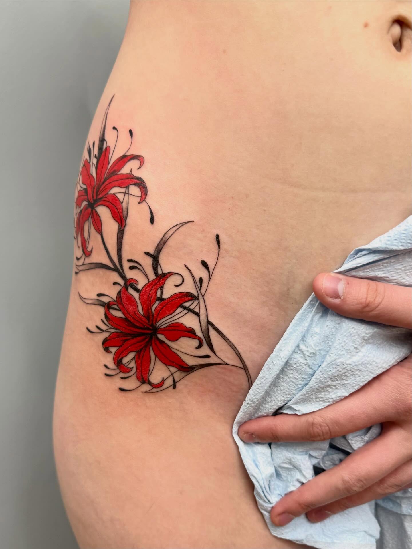 Red lilies dotwork tattoo on the shoulder by Emmy