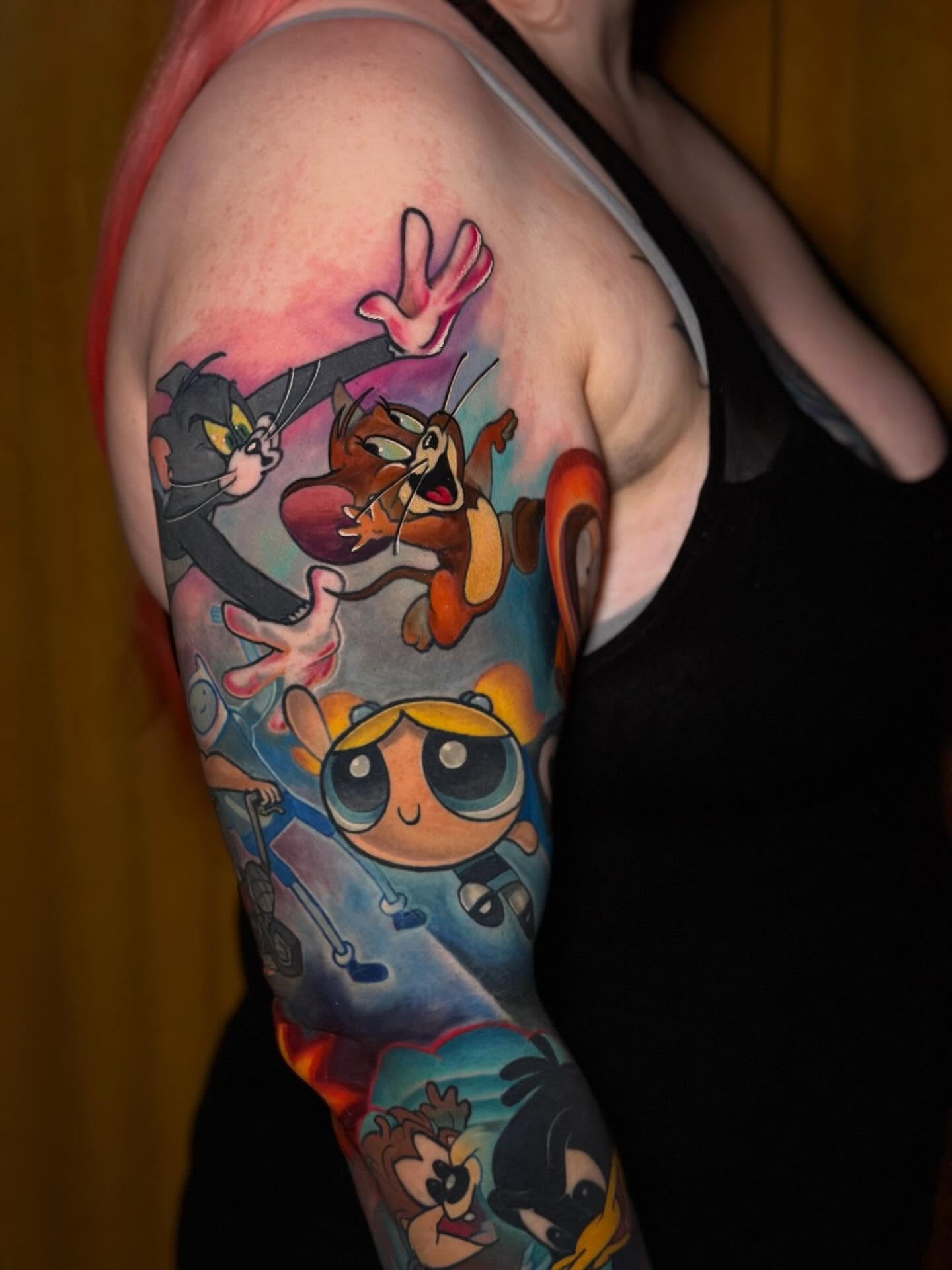 Cartoon characters realism tattoo on the upper arm by Johnny Scillieri