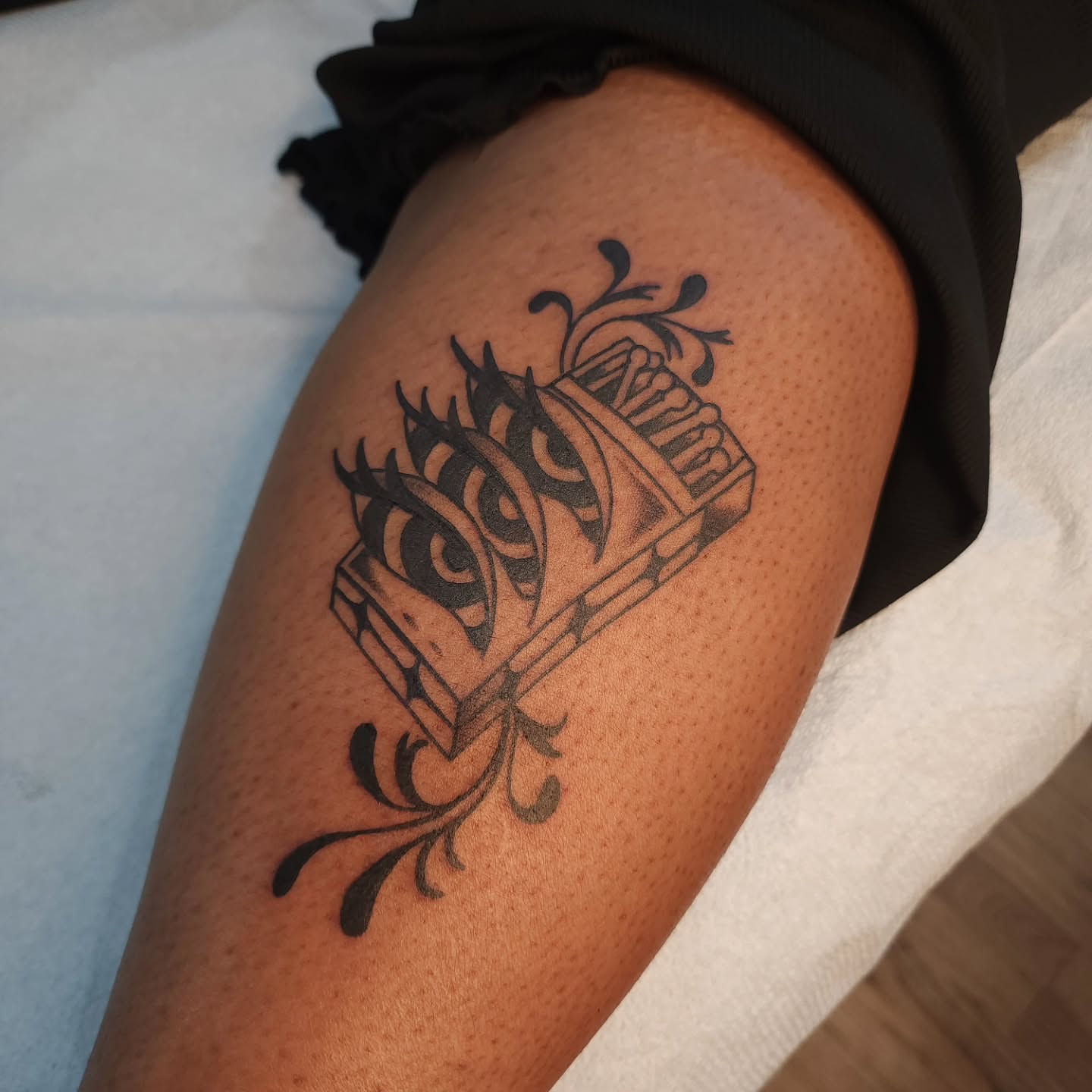 Accordion black and grey tattoo on the thigh by Maxine Stewart