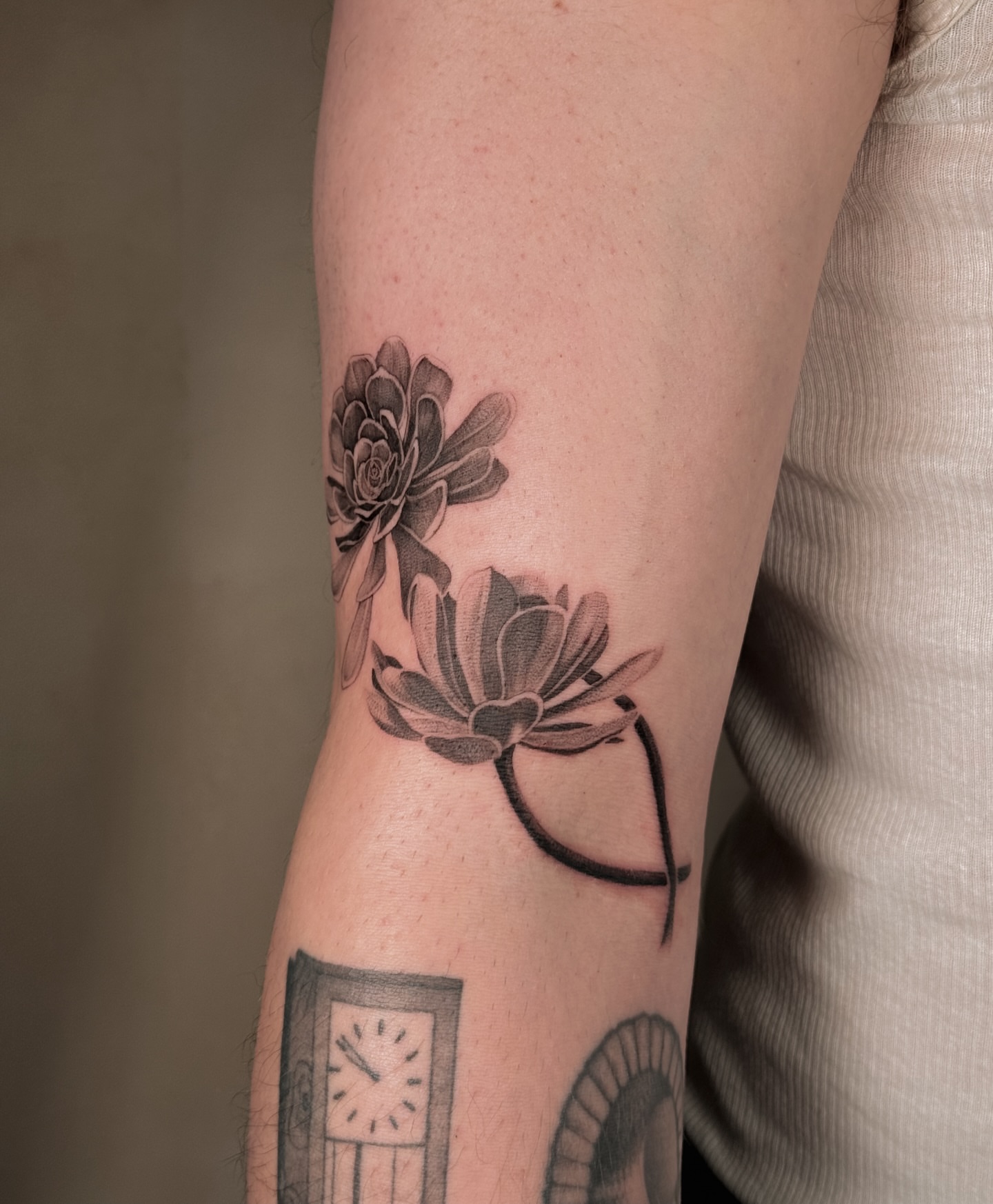 Lotus flowers black and grey tattoo on the forearm by Floral