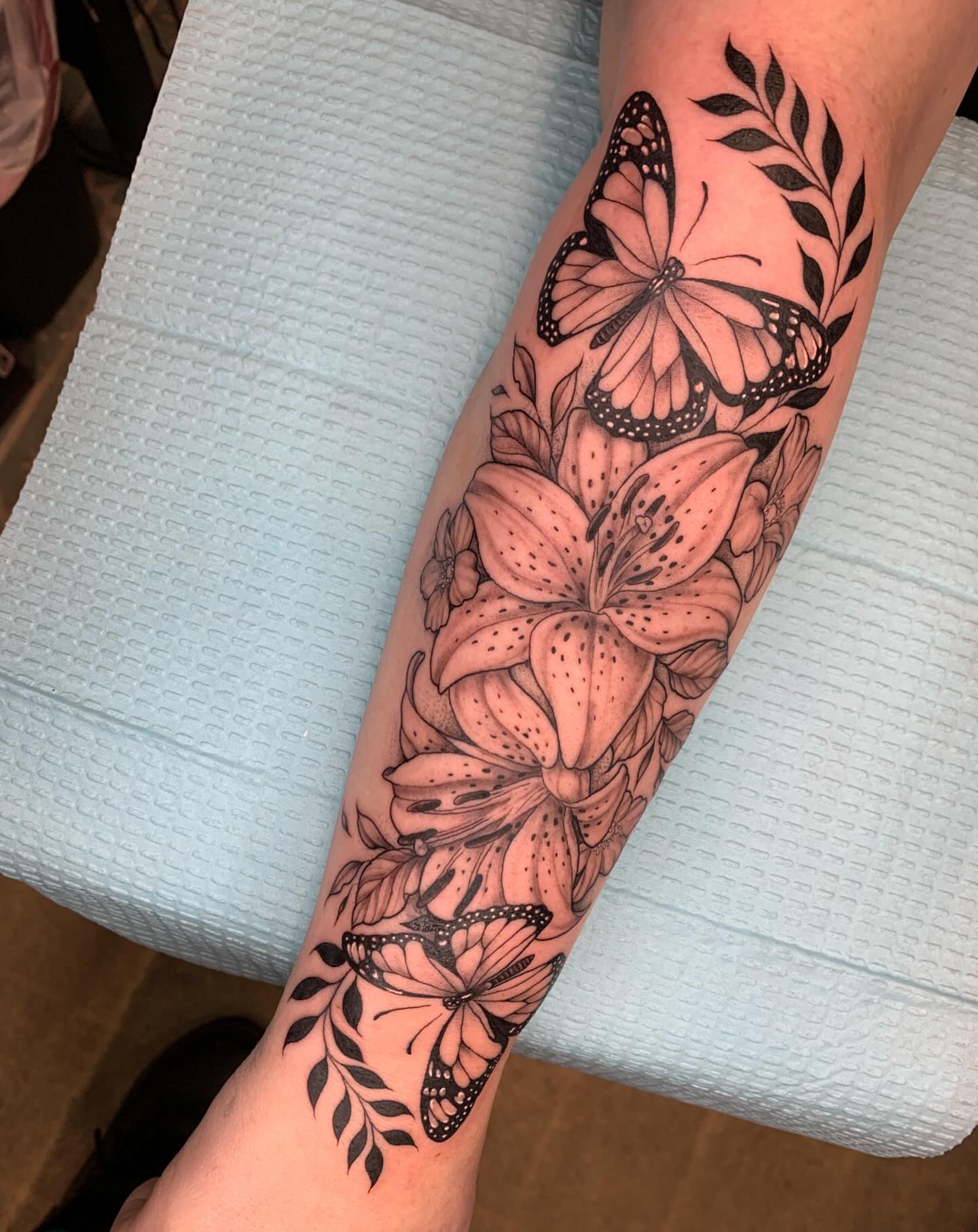 Lilies and butterflies realism tattoo on the forearm by Kitty Jones, Berkeley, California