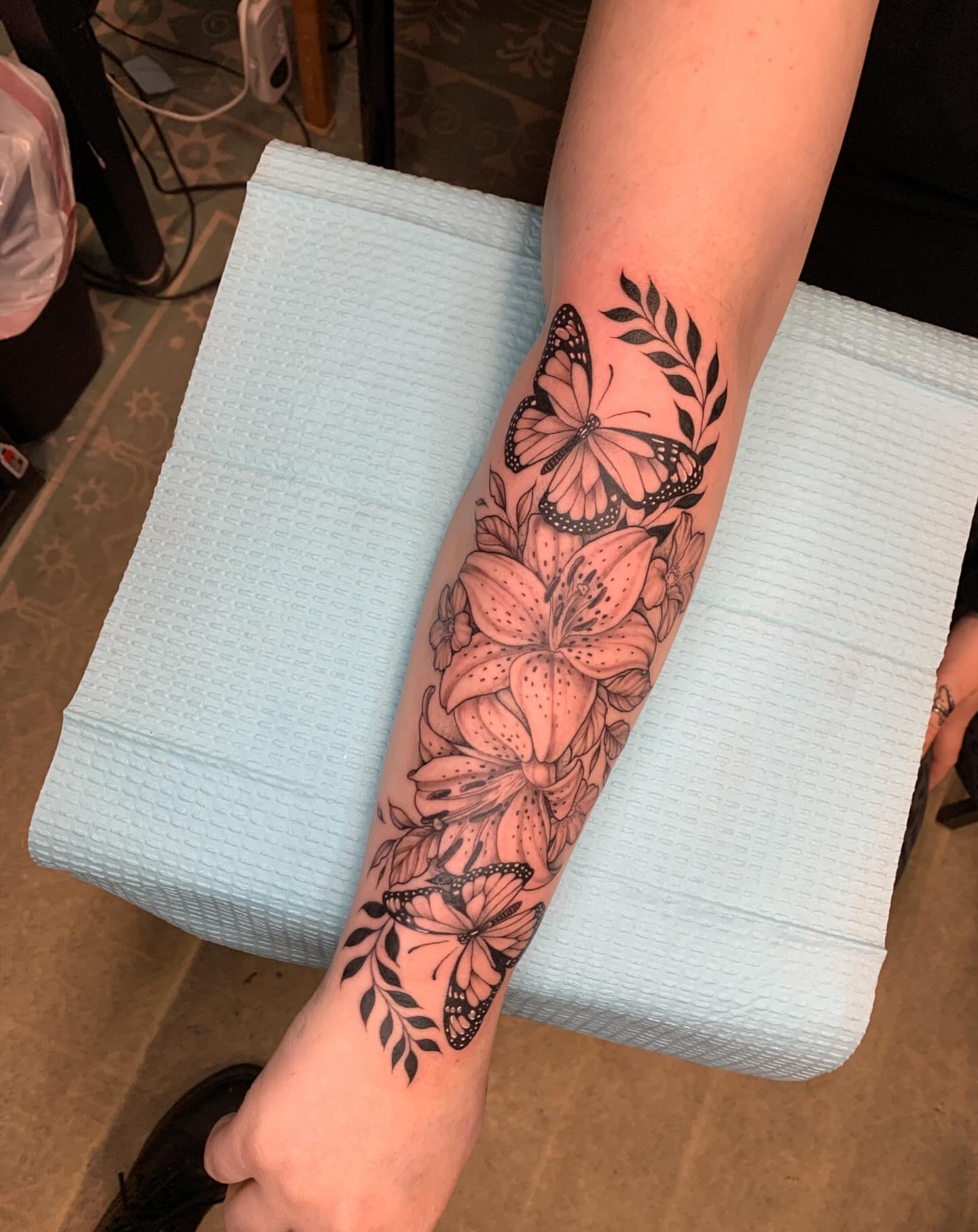 Lily and butterflies black and grey tattoo on the forearm by Kitty Jones, Berkeley, California