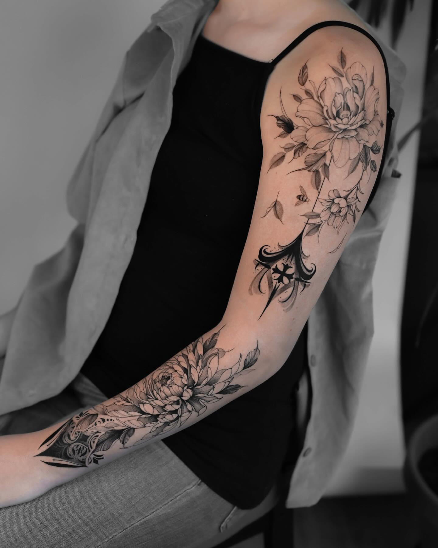 Floral bouquet black and grey tattoo on the upper arm by Anastasiia