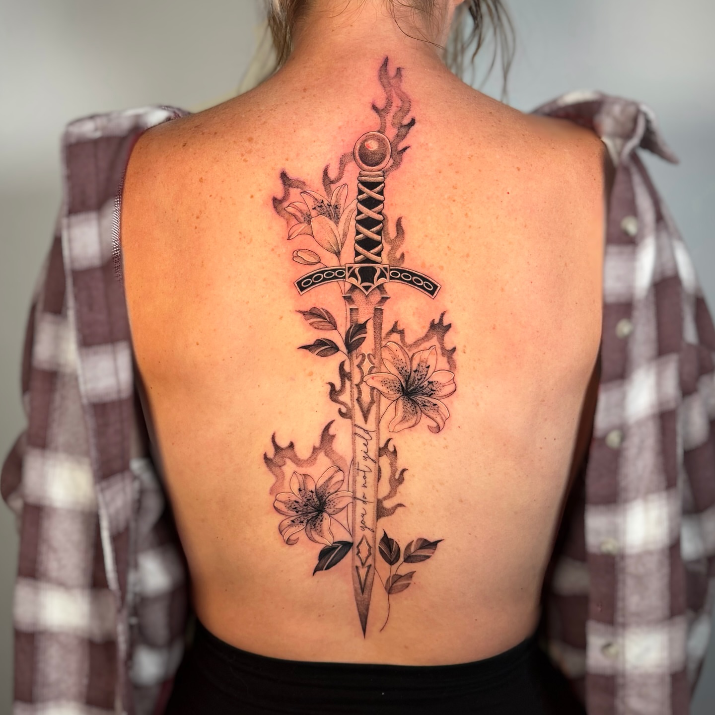 Sword and flowers realism tattoo on the back by Cyn