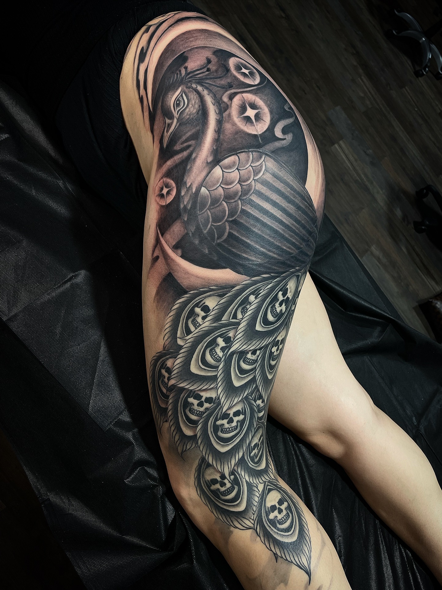 Crow and skulls realism tattoo on the upper arm by Alex Ortiz