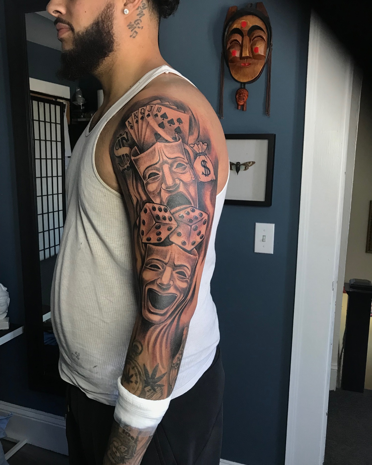Theater masks and playing cards realism tattoo on the upper arm by German Romero-Rendon