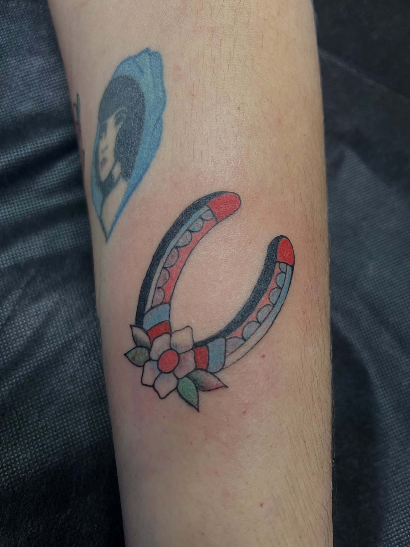 Horseshoe with flowers American traditional tattoo on the forearm by Andrea Patterson