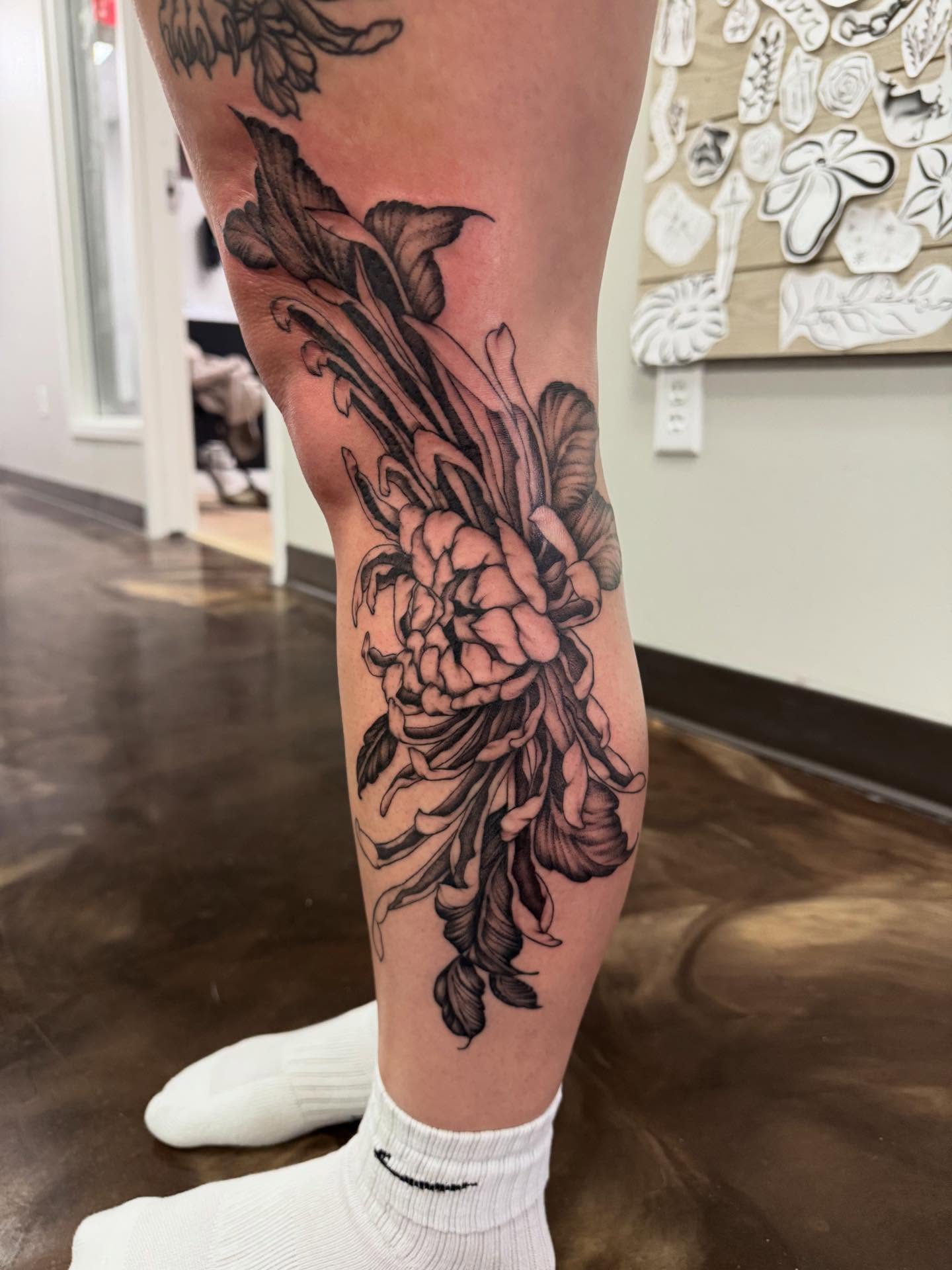 Floral arrangement black and grey tattoo on the calf by Jon Fleming