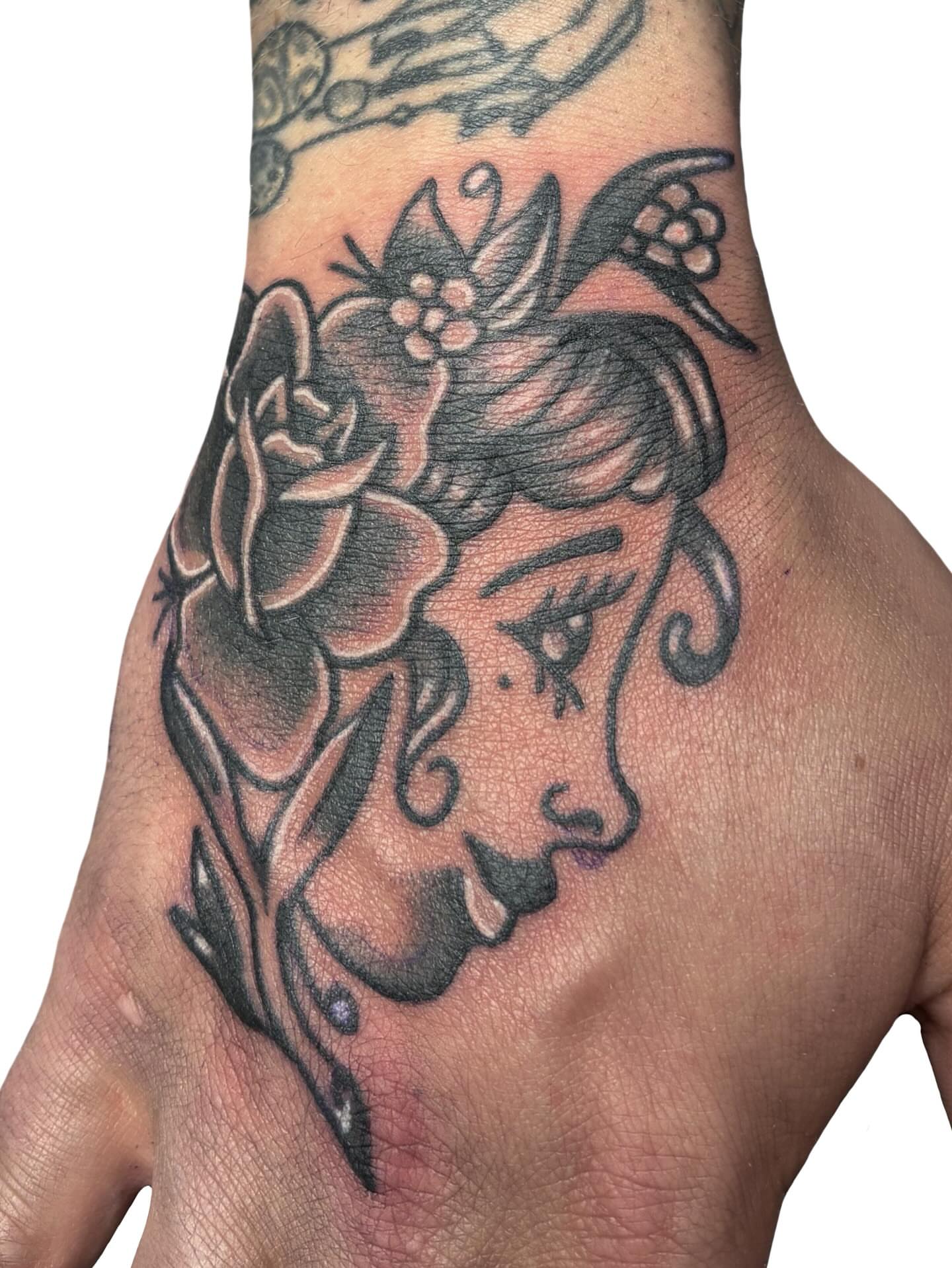 Woman's face American traditional tattoo on the hand by Ava Brady Tattoos