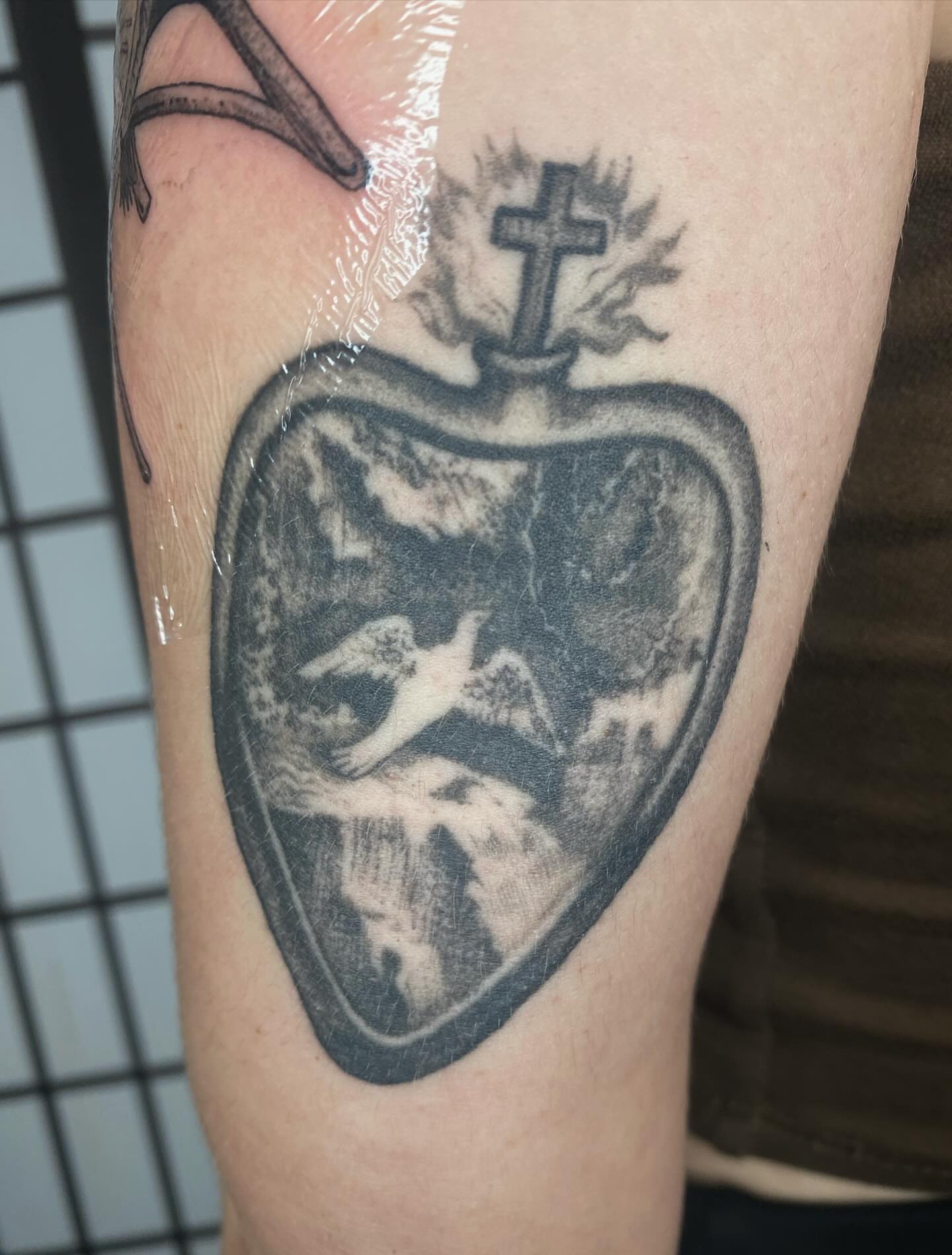 Heart with dove and cross black and grey tattoo on the forearm by sarah 🗝️