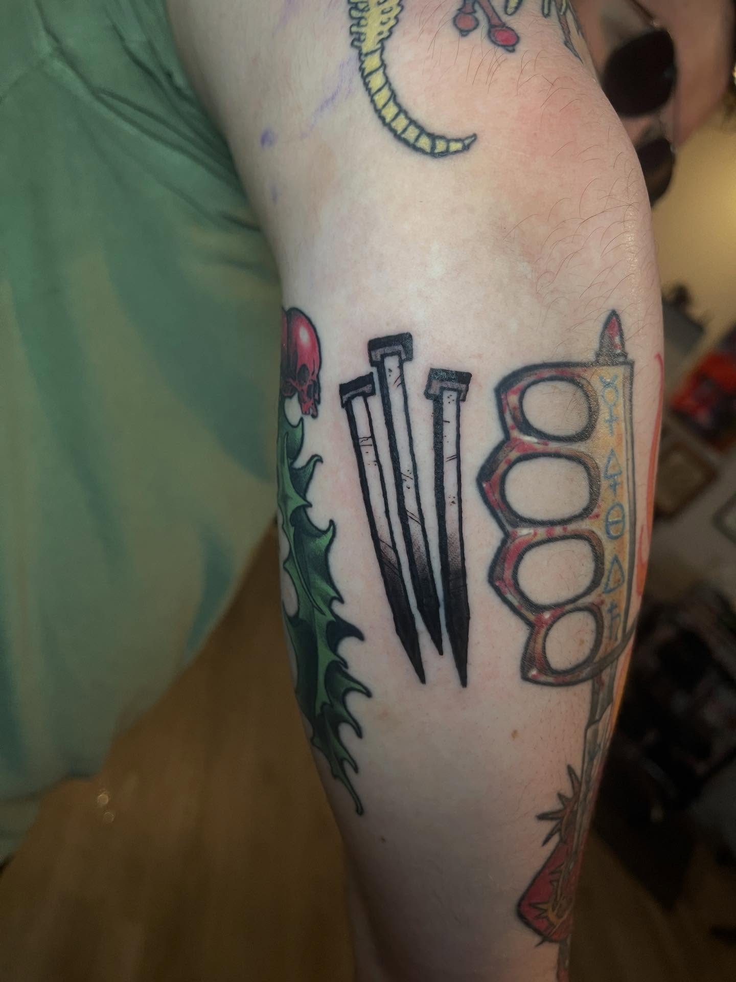 Nails and brass knuckles black and grey tattoo on the forearm by Joe Moreira